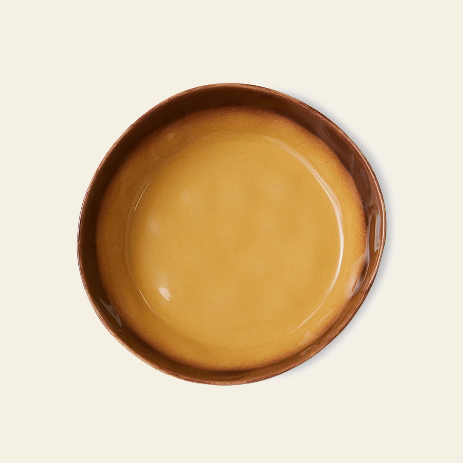 The HKliving 70s Ceramics Pasta Bowls, Set of 2, feature a glossy golden-yellow center and brown rim—retro-inspired tableware photographed from above on a beige background, perfect for vintage lovers.