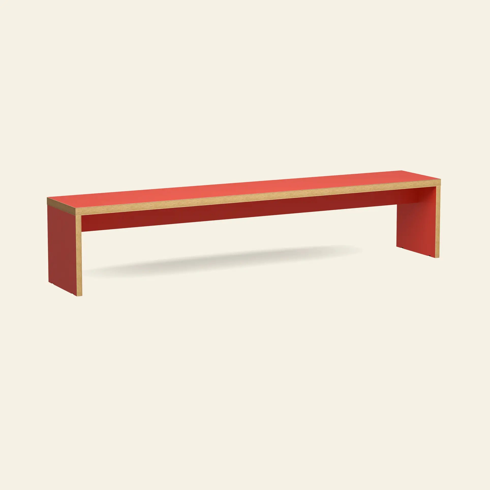 The HKliving Bench, 220cm by HKliving is a minimalist red wooden bench with exposed edges, ideal as space-saving seating for dining tables or entryways. Shown against a plain beige background.