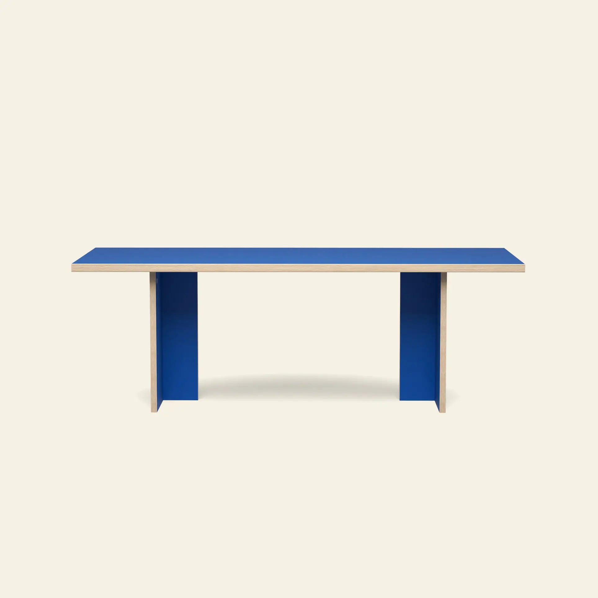 The HKliving Dining Table, Rectangular, 220cm, features a bright blue top and matching vertical panel legs—its minimalist design adds timeless style to any space, shown here against a light beige background.