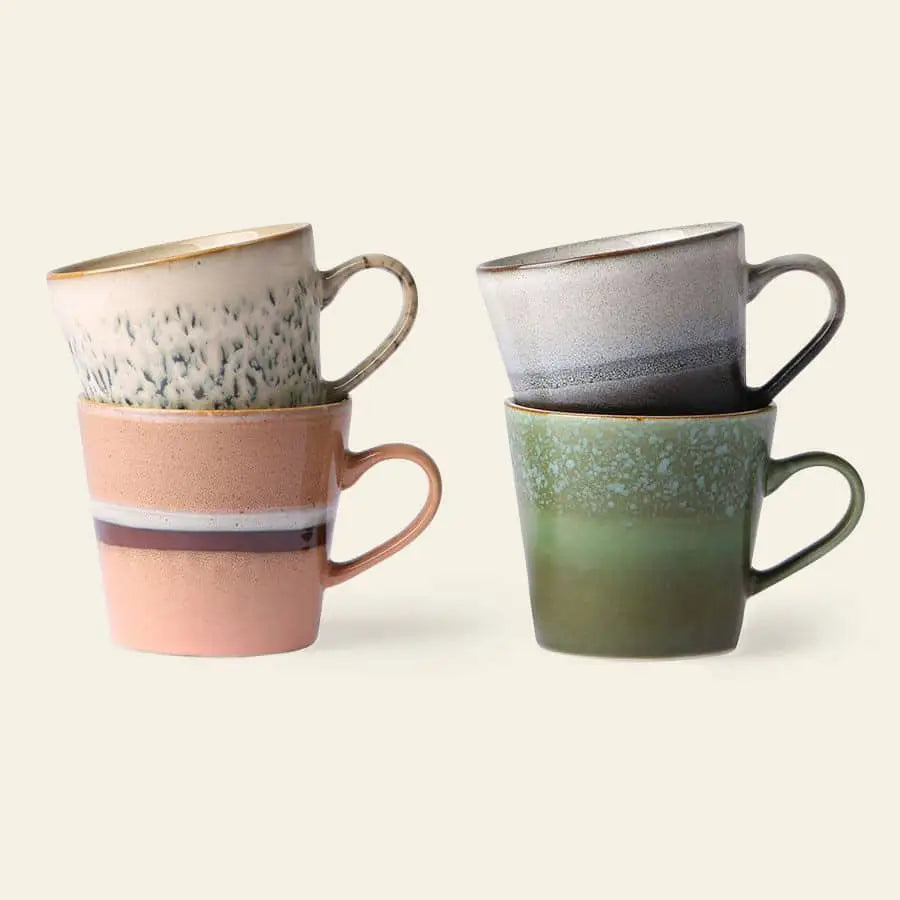 Four HKliving 70s Ceramics Cappuccino Mugs, Set of 4, are stacked in pairs against a light background—the left pair in beige and pink hues, the right in gray and green—ideal for stylish coffee bar decor.