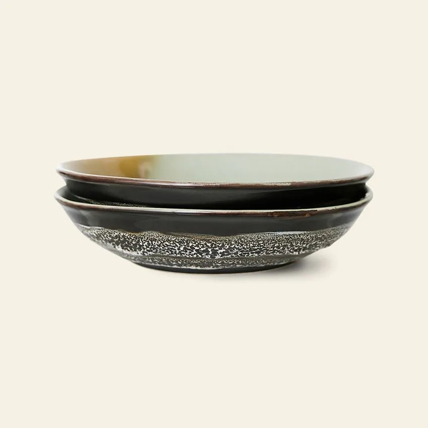 The HKliving 70s Ceramics: Curry Bowls, Set of 2, features shallow, round bowls with dark exteriors and textured speckled designs, adding a vintage touch to your table.
