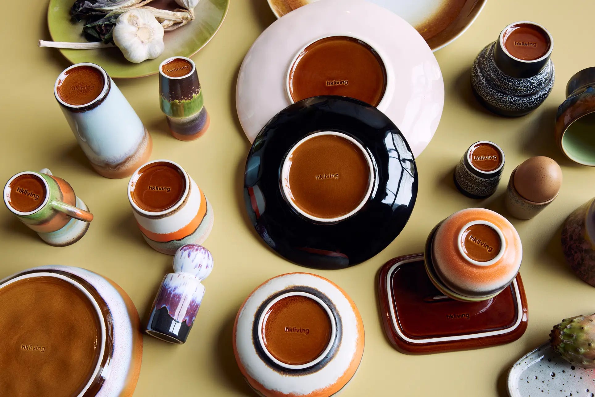 A set of HKliving 70s Ceramics Curry Bowls (set of 2) is displayed upside down on a yellow surface, revealing their brown bases stamped with the HKliving brand name.