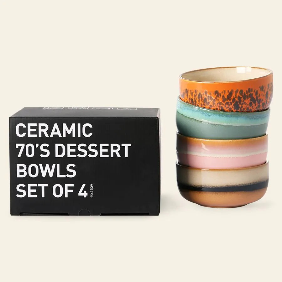 A stack of four HKliving 70s Ceramics Dessert Bowls, each with a unique retro-inspired color and pattern, is displayed beside the branded black box labeled “HKliving 70s Ceramics: Dessert Bowls, Set of 4.”.