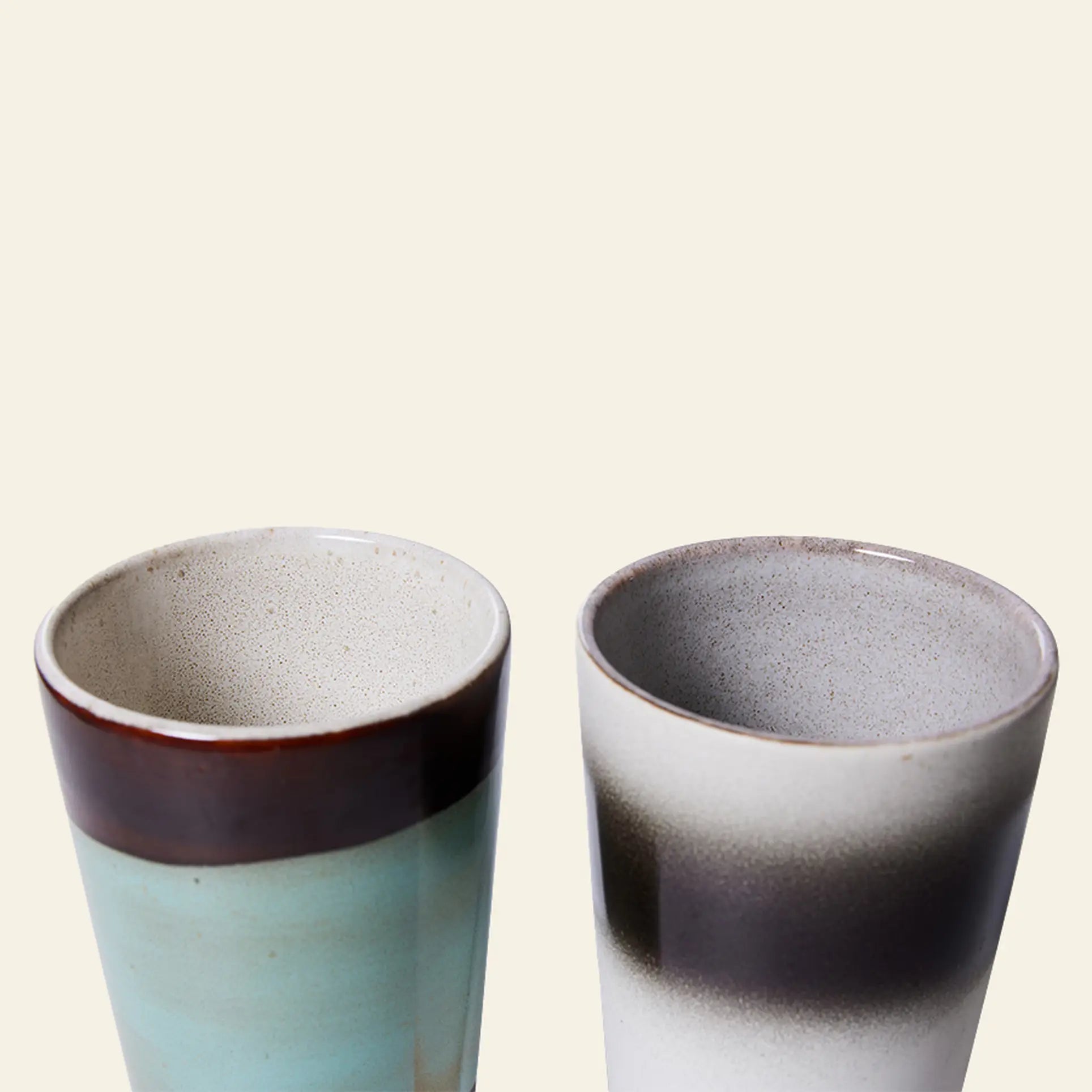 The HKliving 70s Ceramics: Latte Mugs Set of 2 features tall, smooth-glazed mugs—one in light blue with a brown rim, the other in white with a dark brown and gray gradient—both by HKliving, shown against a plain background.