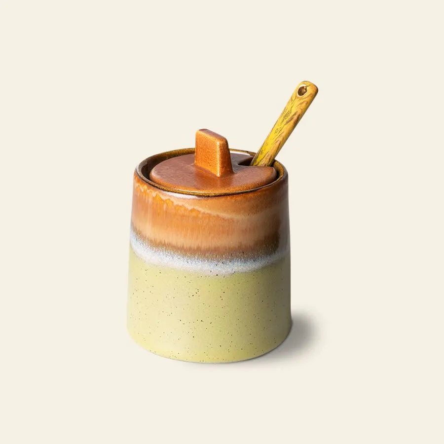 The HKliving 70s Ceramics: Milk Jug & Sugar Pot features earthy-toned gradient design, a lid with a rectangular handle, and includes a wooden spoon, capturing vintage style.