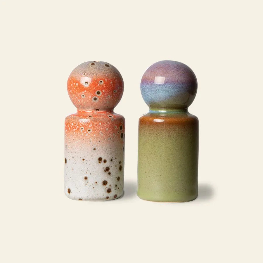 Two HKliving 70s Ceramics shakers evoke retro charm: the left is orange and white with brown speckles; the right, the HKliving 70s Ceramics Pepper & Salt Jar, features green with a gradient of purple, blue, and brown at the top.