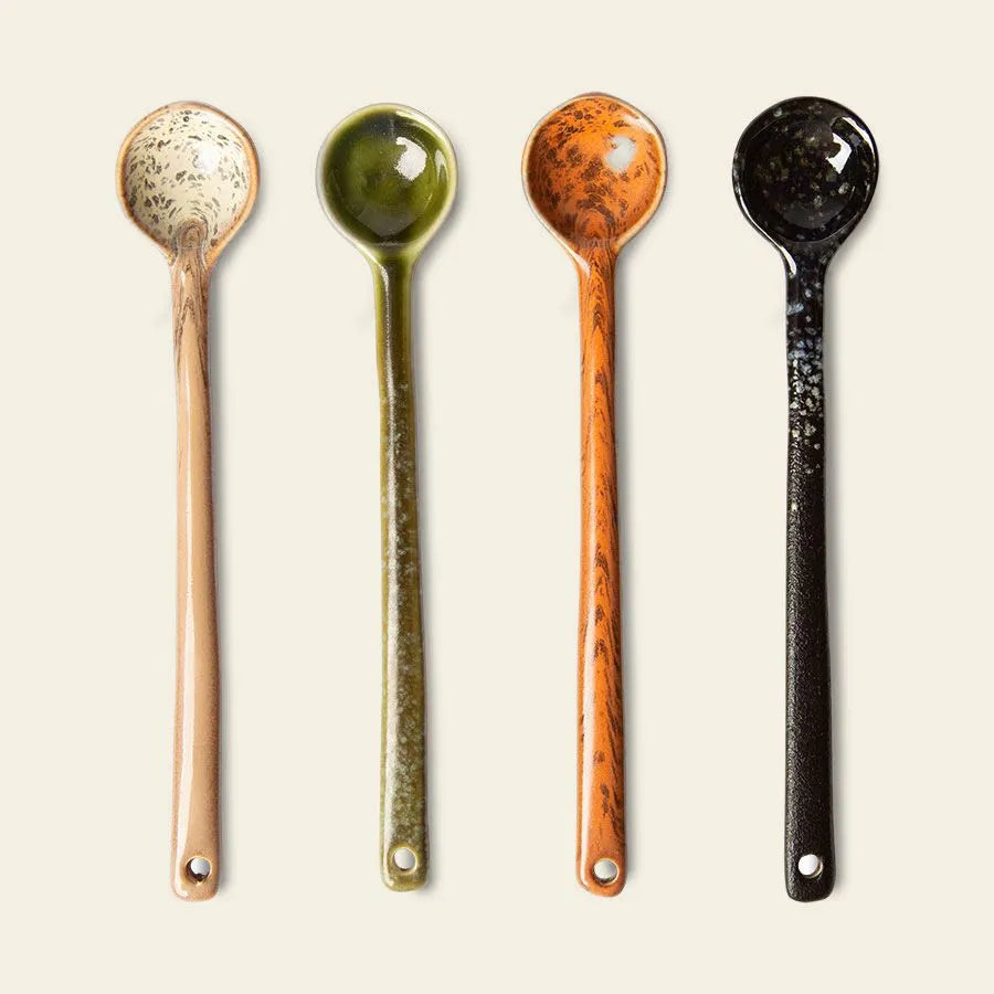 The HKliving 70s Ceramics: Spoons L, Set of 4 features long-handled ceramic spoons in beige, green, orange, and black with a speckled pattern and small hole—ideal for serving coffee or tea—by HKliving.