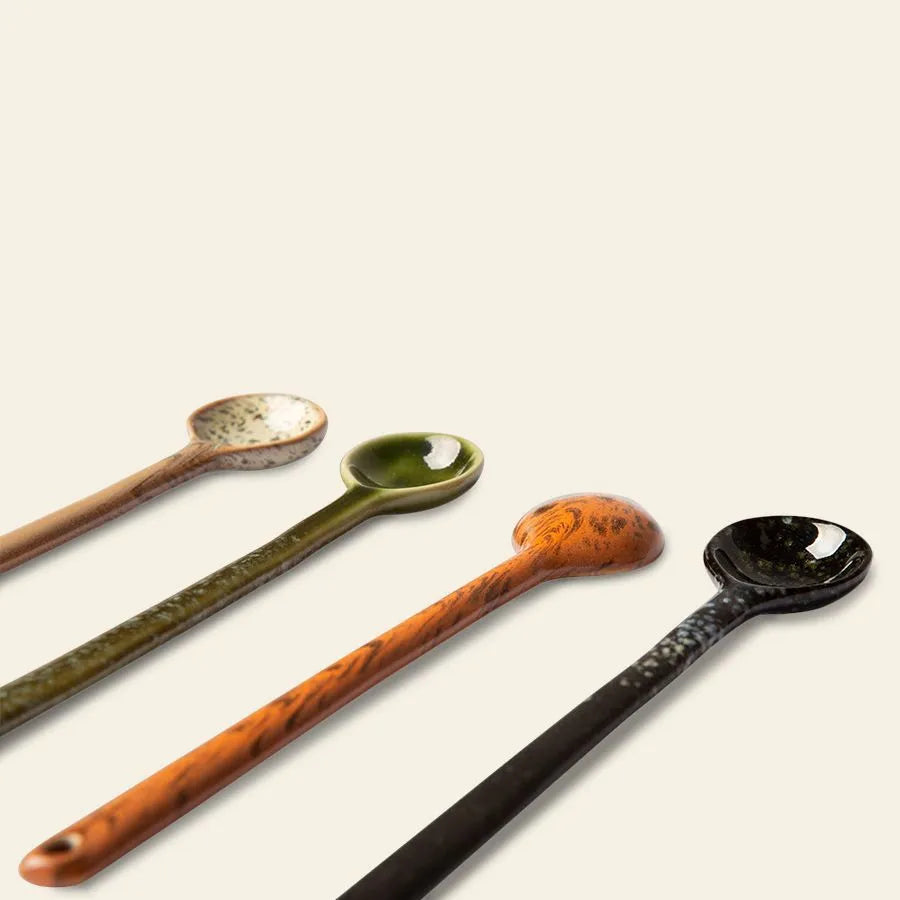The HKliving 70s Ceramics: Spoons L, Set of 4 features ceramic spoons in beige, green, orange, and black—perfect for stirring your favorite coffee or tea. Diagonally arranged on a light background for a retro touch.