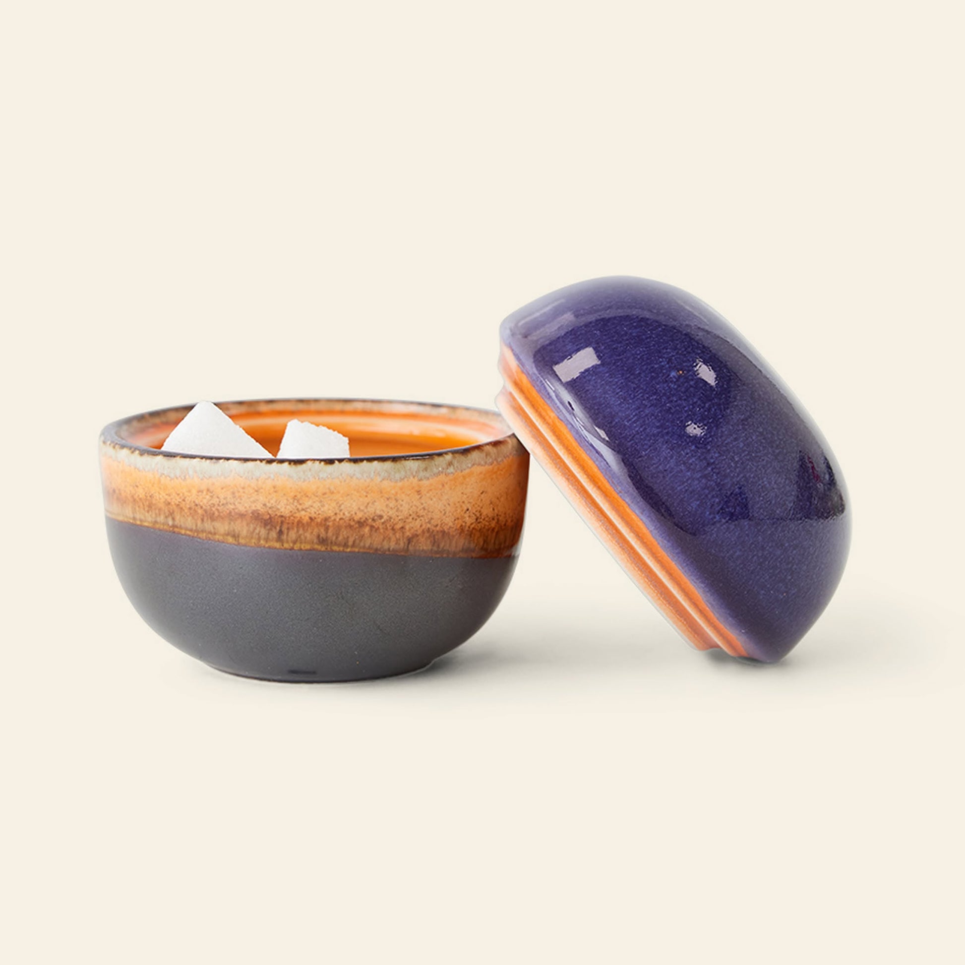 The HKliving 70s Ceramics Sugar Pot is a small ceramic bowl with a purple and orange lid, featuring earthy gradient tones and a glossy finish—perfect from HKliving for storing condiments or sugar.