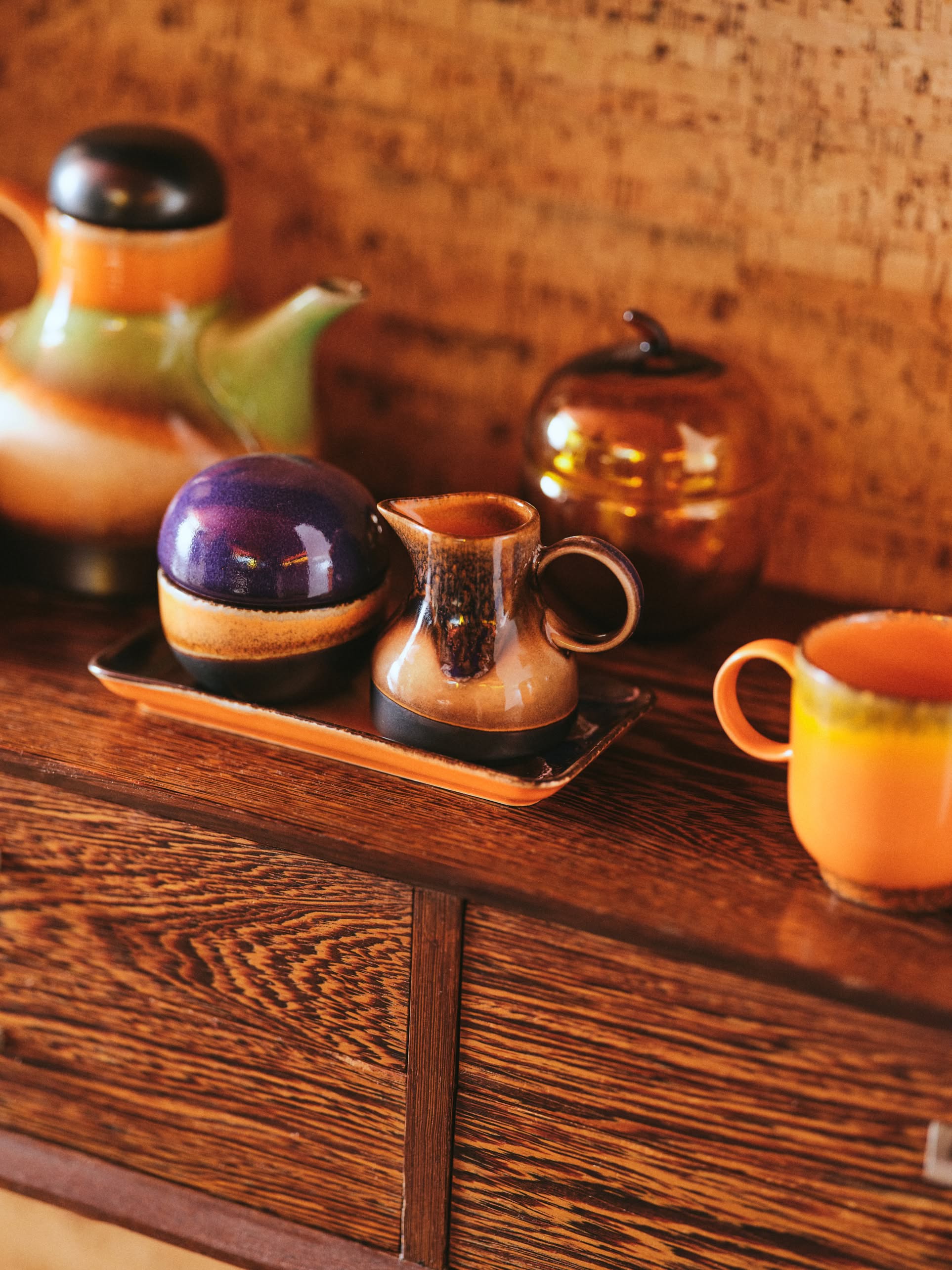 A stylish retro display featuring HKlivings 70s Ceramics: Sugar Pot, teapot, creamer, mug, and covered dish on wood—a versatile collection by HKliving for storing condiments in vintage-inspired style.