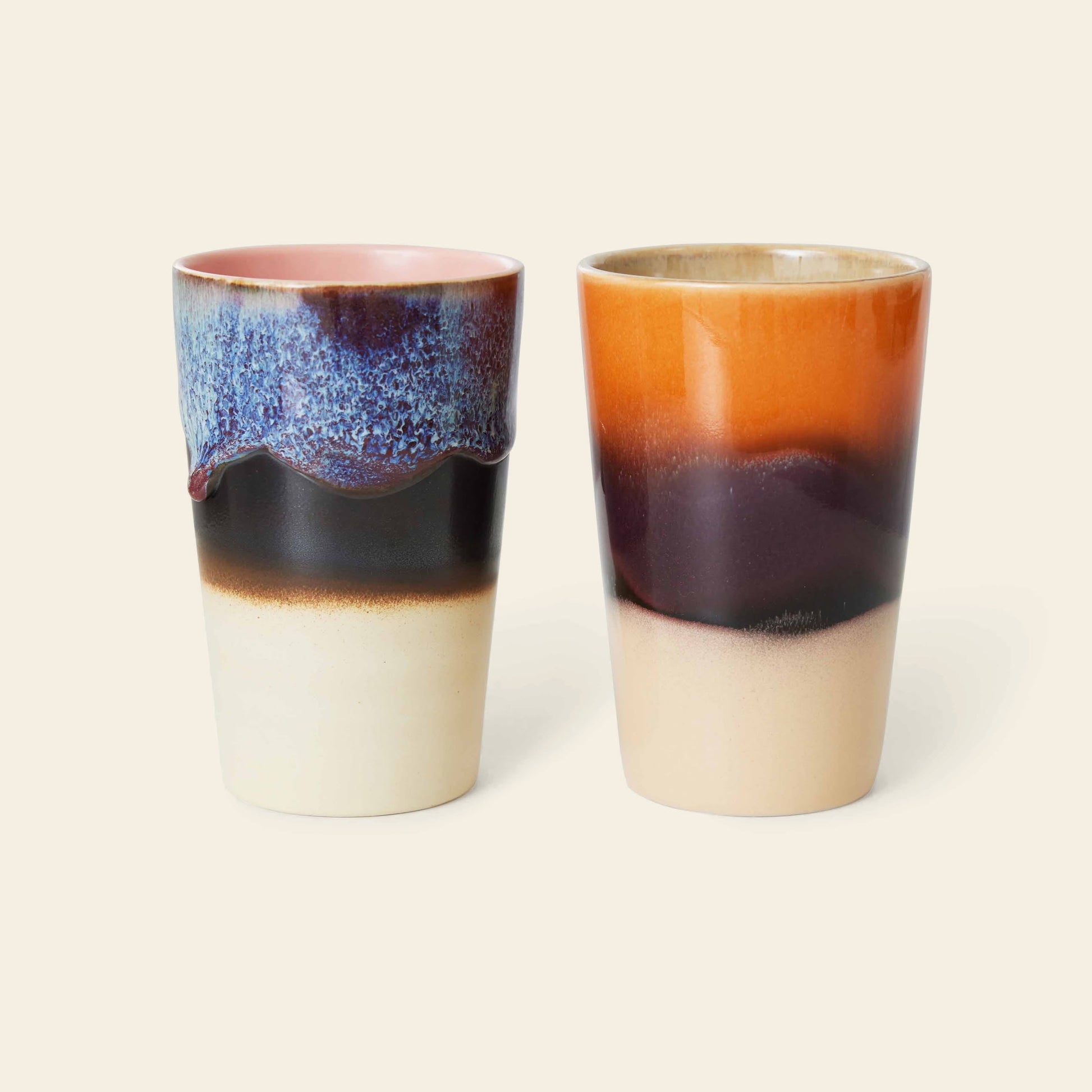 The HKliving 70s Ceramics Tea Mugs, Set of 2, feature unique retro-inspired glaze patterns: one with blue, purple, and cream hues; the other with orange, brown, and cream accents—all on tall ceramic mugs.