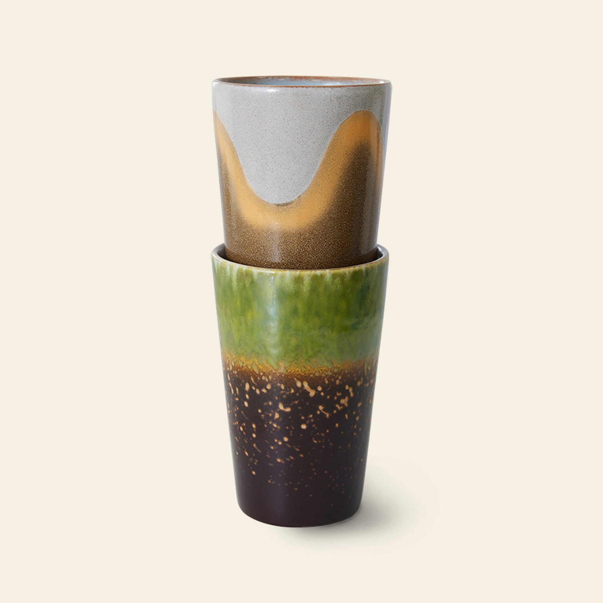 The HKliving 70s Ceramics: Tea Mugs, Set of 2 features retro-inspired glazes—one with wave patterns in gray, tan, and brown; the other with green, brown, and gold speckles—adding a unique touch to any setting.