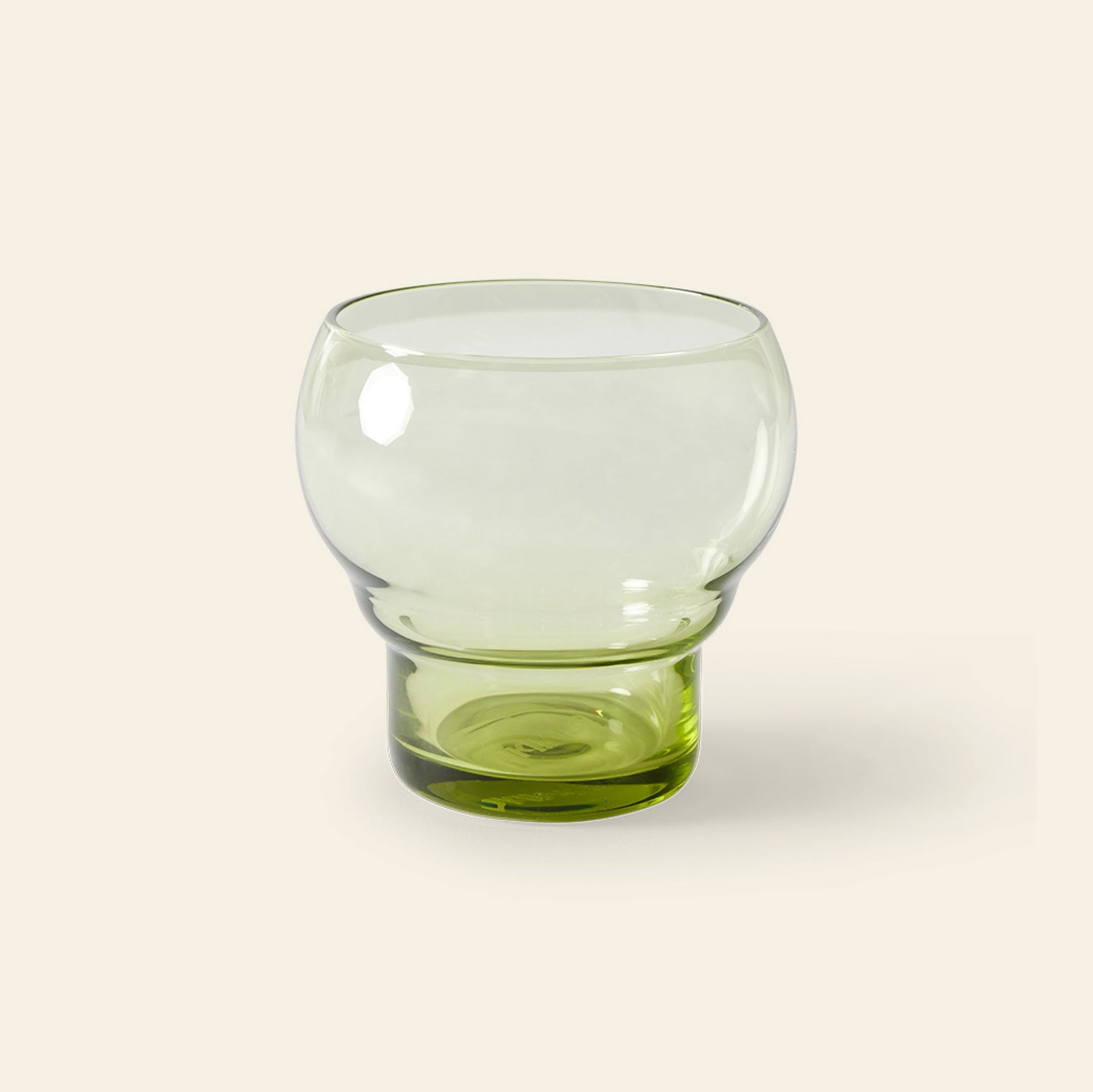 The HKliving 70s Glassware: Bulb Glasses, Set of 4 features transparent glasses with a rounded bowl and thick green-tinted base, showcasing retro sophistication against a plain light beige background.