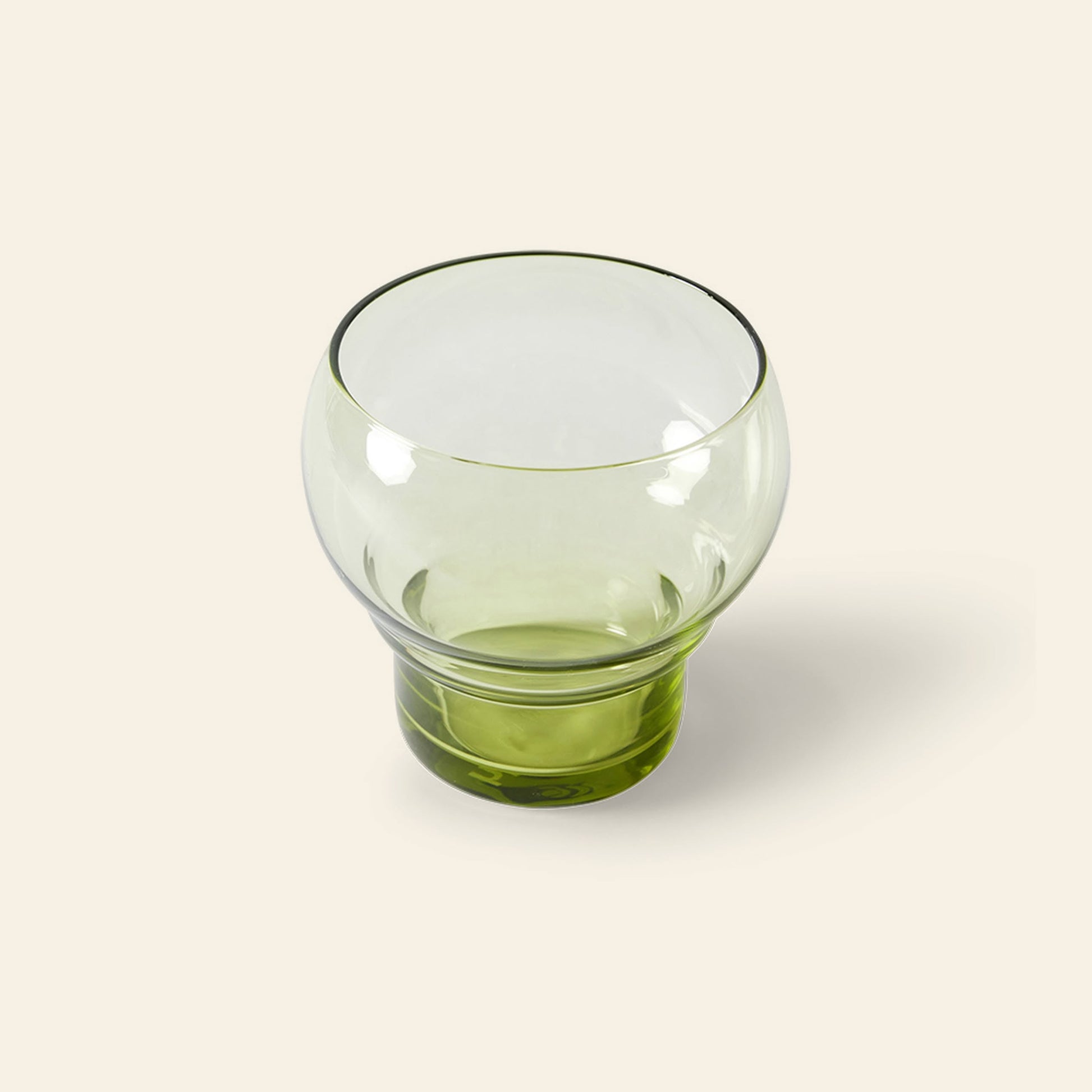 The HKliving 70s Glassware Bulb Glasses, Set of 4, feature round transparent green cups with wide bowls and thick short bases, set against a light beige background for a retro sophisticated look.