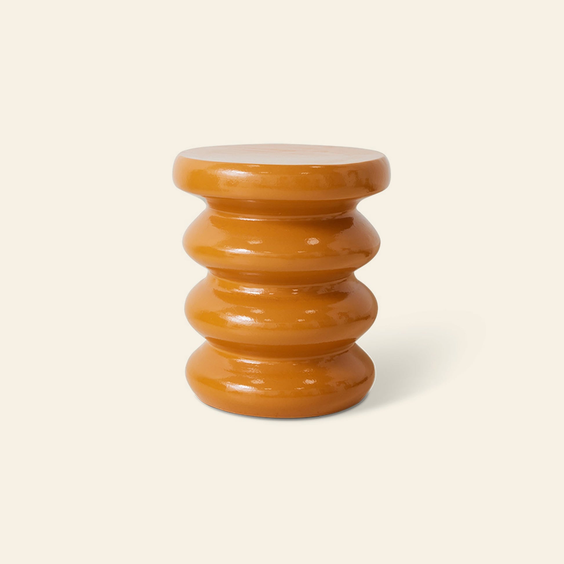The HKliving Allure Side Table by HKliving features a small, glossy orange round top and four rounded, wavy stacked sections, adding modern sophistication to any plain cream background.