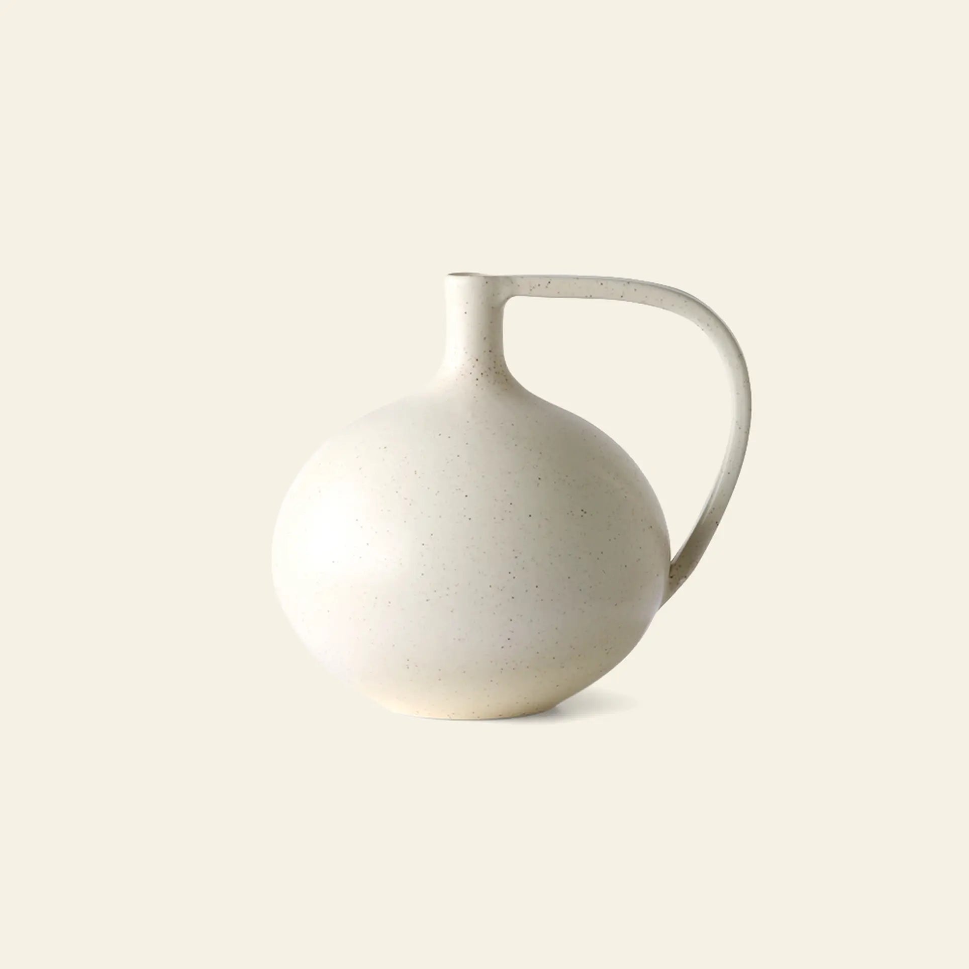 The HKliving Ceramic Jar M by HKliving features a rounded, soft white speckled design with a narrow neck and large curved handle, capturing Mediterranean charm against a plain, light background.