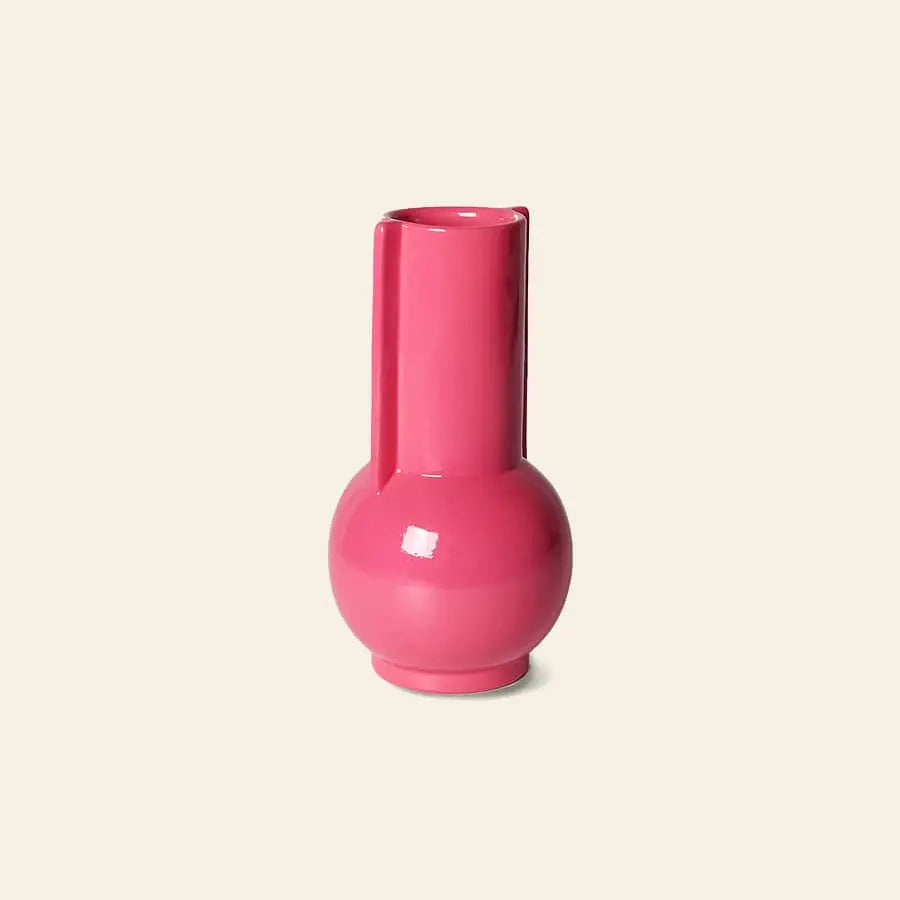 The HKliving Ceramic Vase Hot Pink by HKliving features a vibrant glossy pink finish, round base, and tall cylindrical neck, radiating playful charm against a simple beige background.