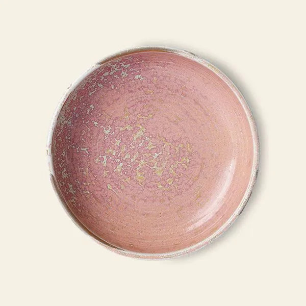 The HKliving Chef Ceramics: Deep Plate M by HKliving features a soft pink reactive glaze with delicate speckles, viewed from above on a light beige background, showcasing its artisanal charm.