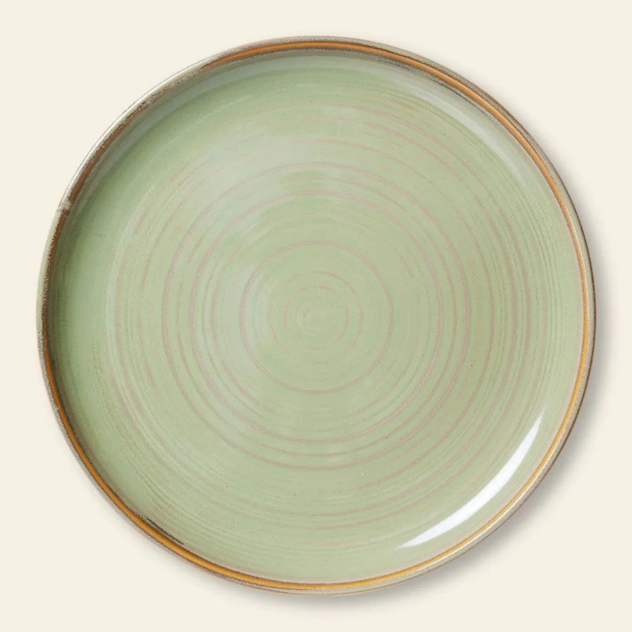 The HKliving Chef Ceramics Dinner Plate features a round ceramic design with a pale green surface, subtle circular lines, and a thin brownish rim with a rustic finish—perfect for timeless tableware. Styled on beige.