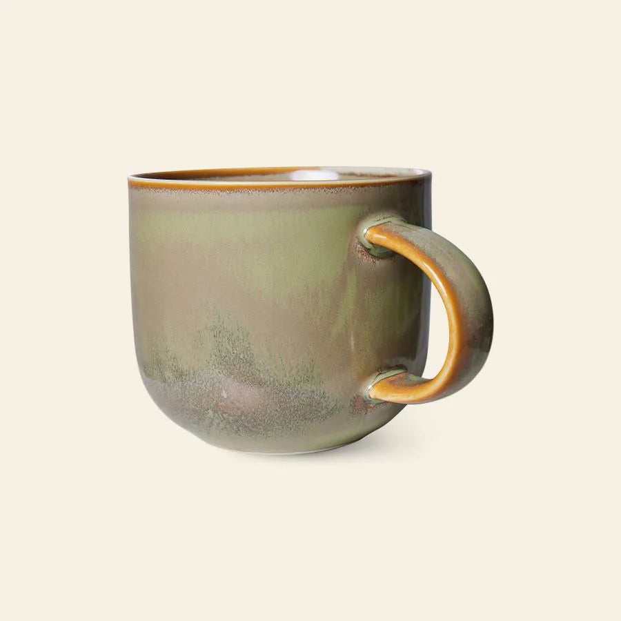 The HKliving Chef Ceramics: Mug by HKliving features a rounded shape, earthy green and brown glaze, and a curved handle—blending artisanal charm with tableware essentials, all set against a plain light background.