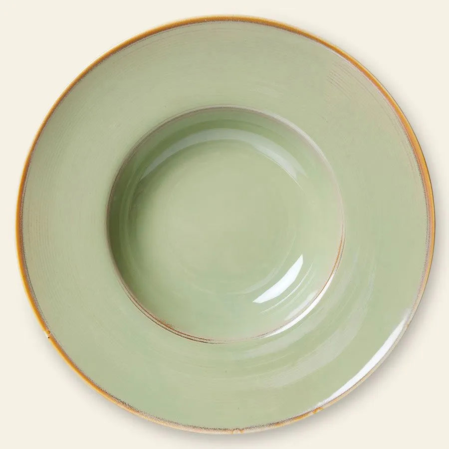 The HKliving Chef Ceramics: Pasta Plate is a round, light green ceramic plate with a wide rim, shallow center, and rustic brown edge. An artisan essential from HKlivings Chef Ceramics collection. Shown on a neutral beige background.