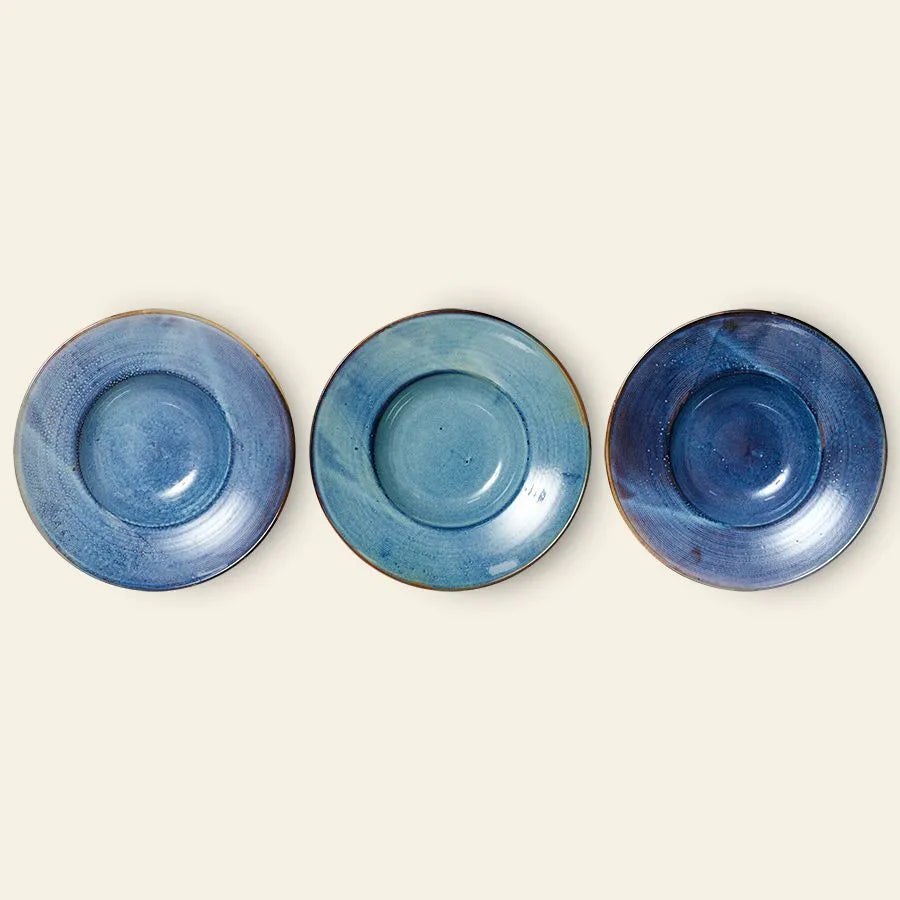 Three HKliving Chef Ceramics Pasta Plates, handmade with blue glaze, show unique shade and texture variations and are arranged in a row on a light beige background.