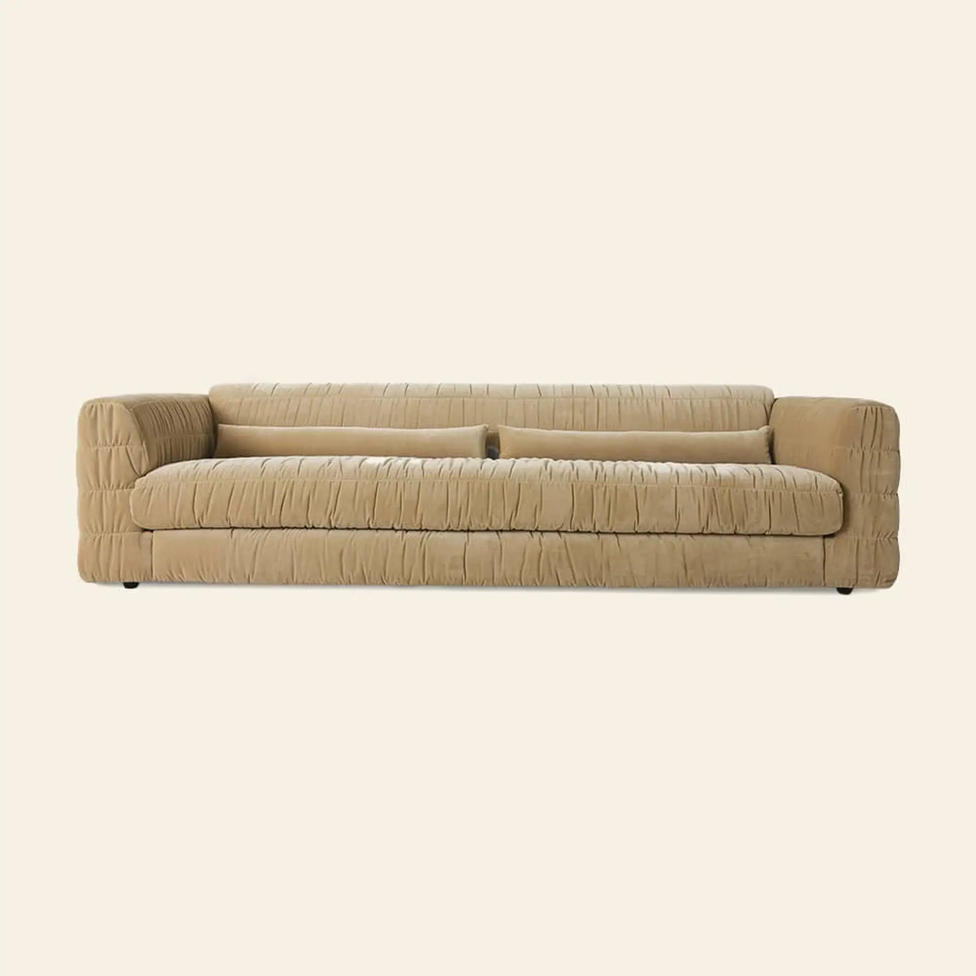 The HKliving Club Couch by HKliving is a tan, modern sofa with a low back and arms, featuring pleated ruched upholstery. Its minimalist design and textured fabric offer enhanced seating comfort against a simple, light backdrop.