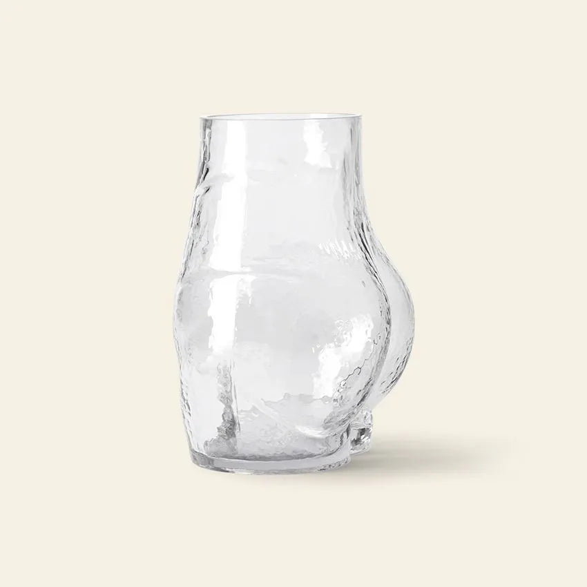 The HKliving Glass Bum Vase by HKliving features a clear, curvaceous silhouette with an irregular sculpted shape and a rounded protruding bulge, shown against a plain off-white background.