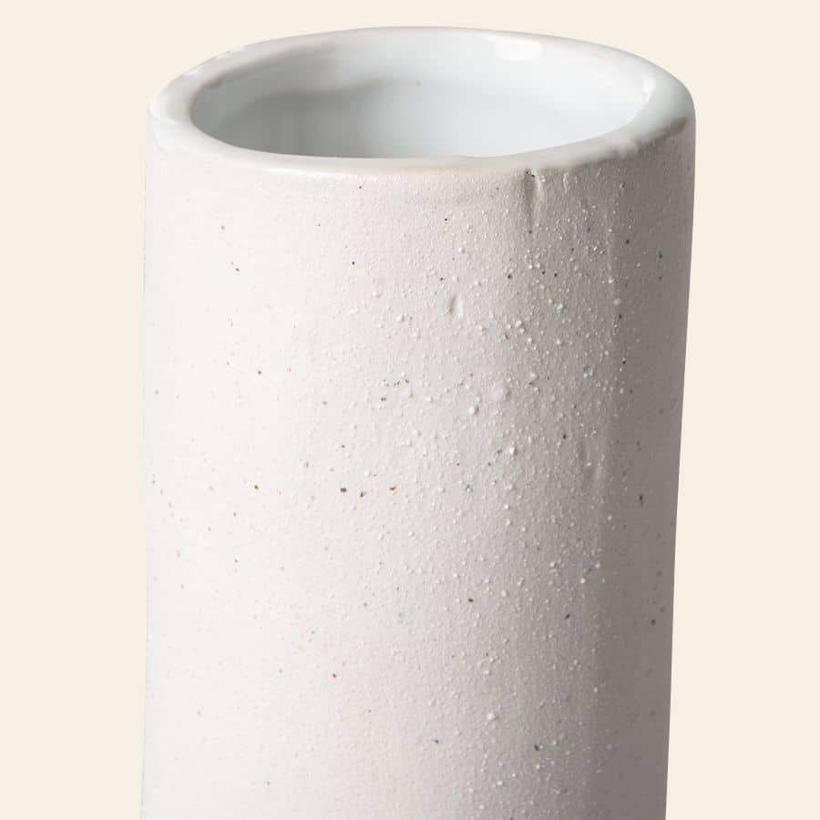 Close-up of the HKliving HK Objects: Ceramic Twisted Vase by HKliving, showcasing its rough, textured white matte exterior and a smooth, glossy interior. This modern sculptural piece is perfect for elegant home decor against a light beige background.