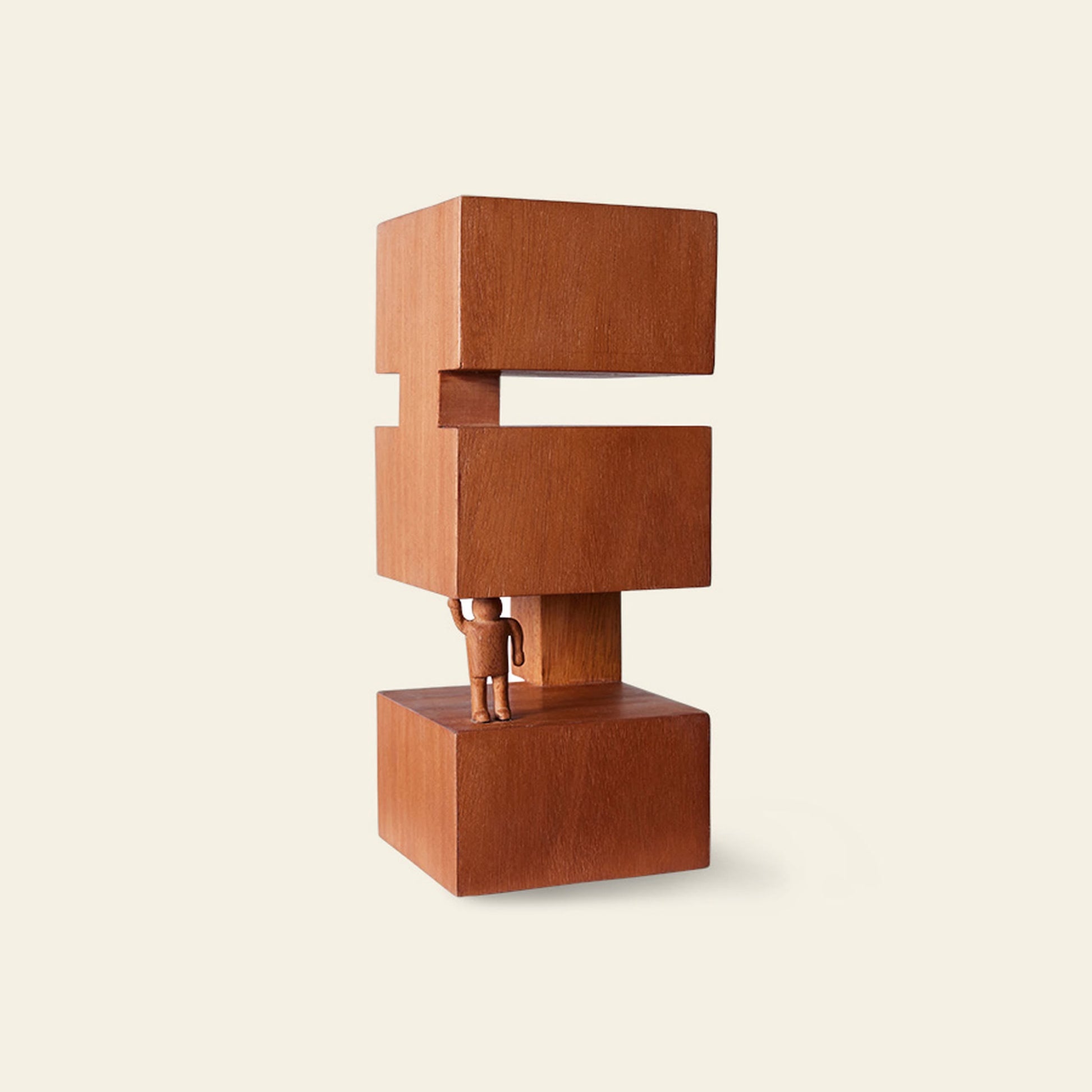 The HKliving HK Objects: Empowered by HKliving features a hand-carved figure holding three stacked, brown wooden blocks with a gap between the top two, evoking Bauhaus minimalism against a plain light background.