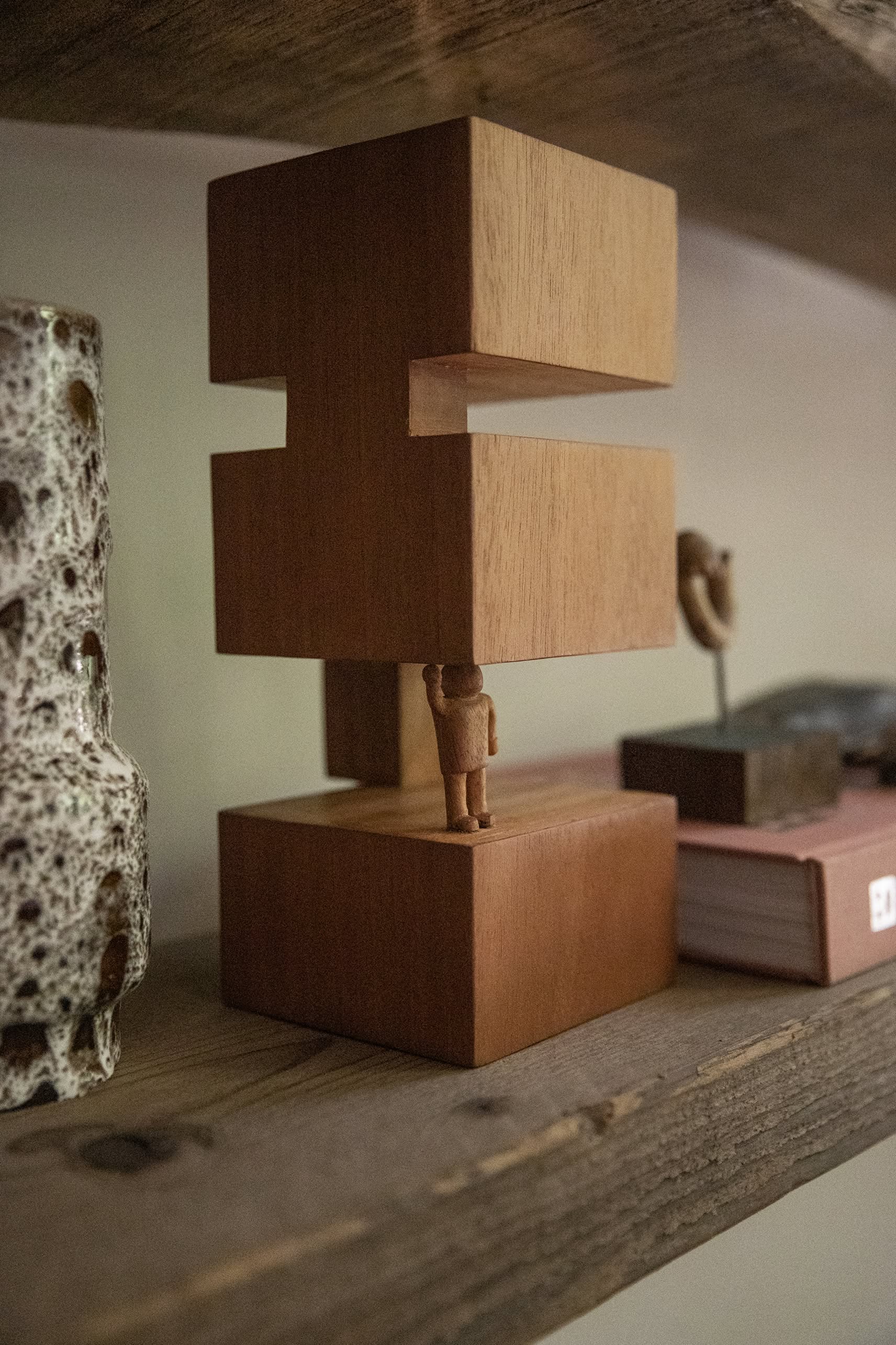The HKliving HK Objects: Empowered by HKliving is a hand-carved figure holding a geometric wooden structure above its head, inspired by Bauhaus design, perfect for display on rustic shelves with decorative accents.
