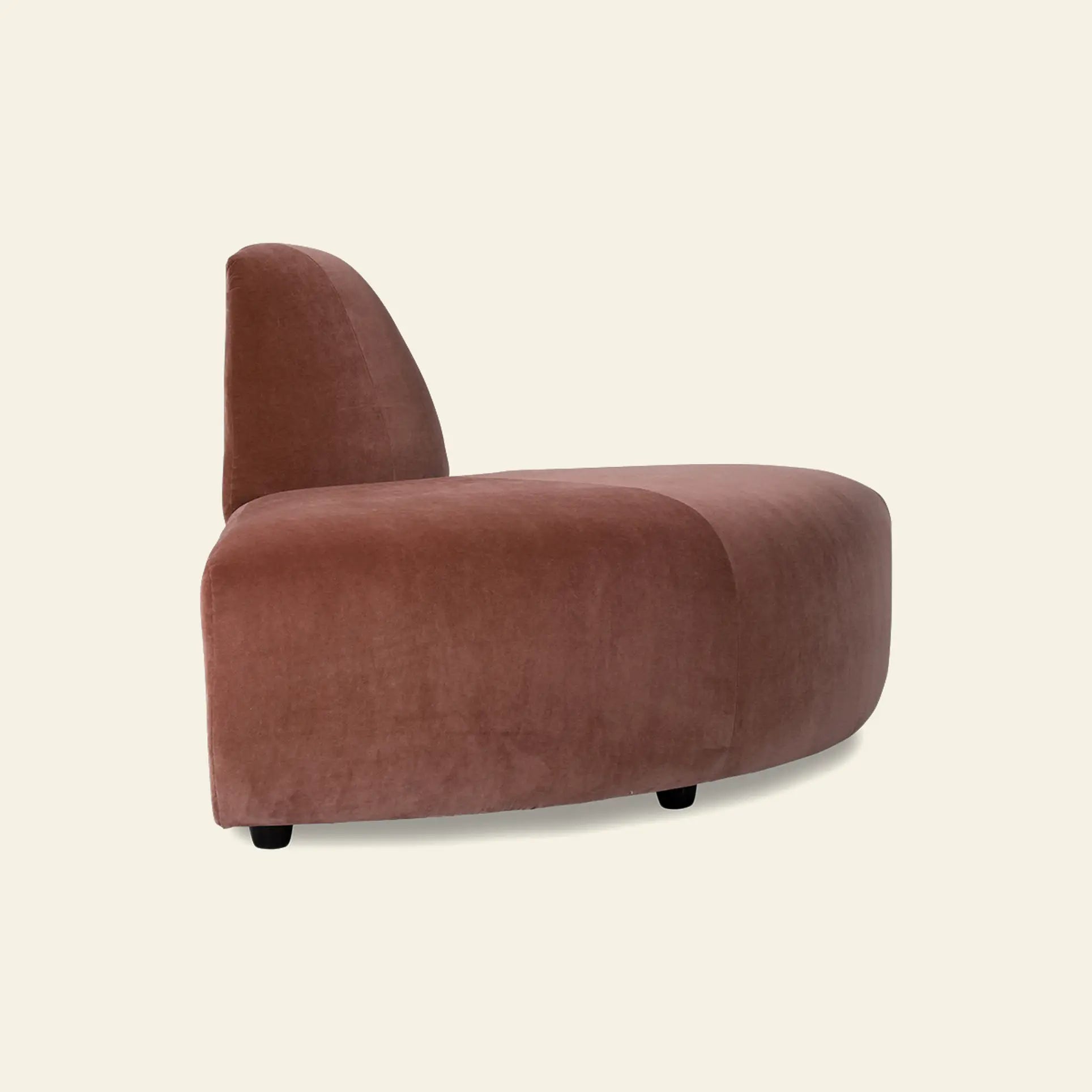 The HKliving Jax Couch, Angle by HKliving is a modern, armless lounge chair with a curved backrest and soft muted pink upholstery, displayed from the side against a plain light background.