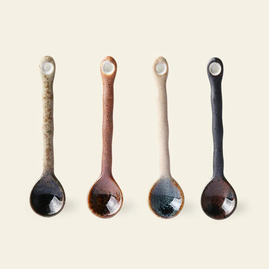 The HKliving Kyoto Ceramics Japanese Tea Spoons set includes four spoons with wavy, textured handles and earthy glazes in beige, brown, off-white, and dark blue—each with a small round hole and inspired by Japanese ceramics.