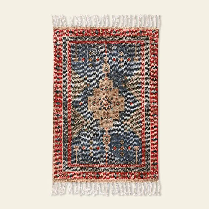 The HKliving Printed Bathmat Overtufted by HKliving features a blue center, beige medallion, red and green accents, red border, and white fringe. Its intricate design and silicone layer add style and safety to any bathroom decor.