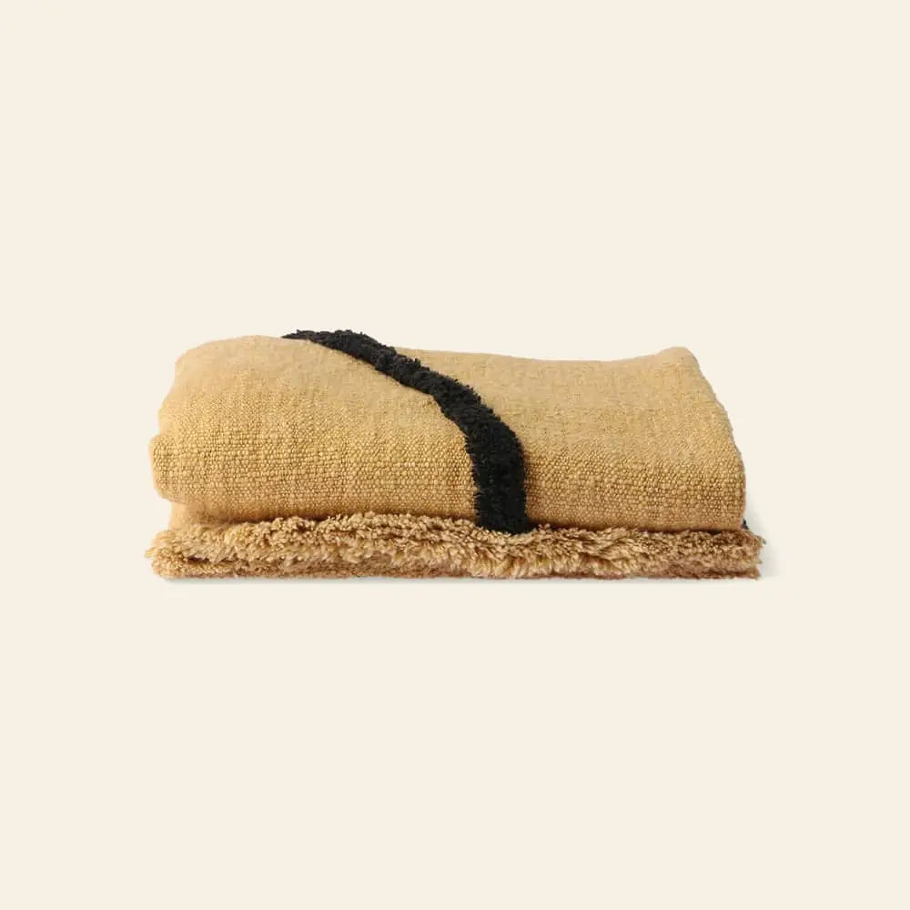 The HKliving Soft Woven Throw with black tufted lines, crafted from cozy cotton, is displayed on a light neutral background.