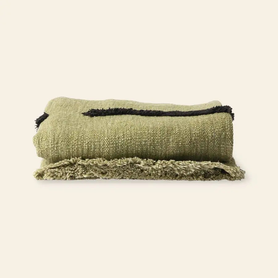 The HKliving Soft Woven Throw With Black Tufted Lines is a cosy folded green cotton throw with textured style, black stripes, and a fringed edge, shown against a simple light background.