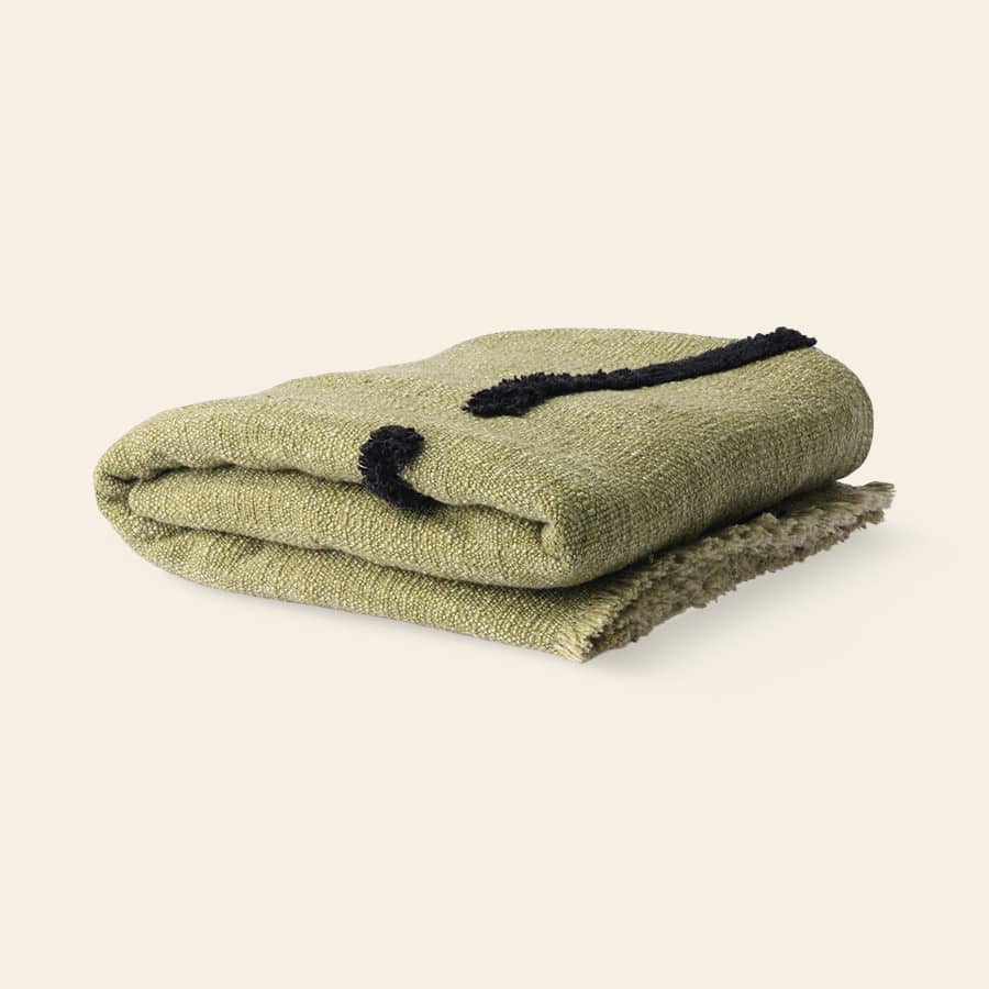 The HKliving Soft Woven Throw With Black Tufted Lines by HKliving features cosy olive green cotton and a stylish black wavy line design, shown folded on a light cream background.