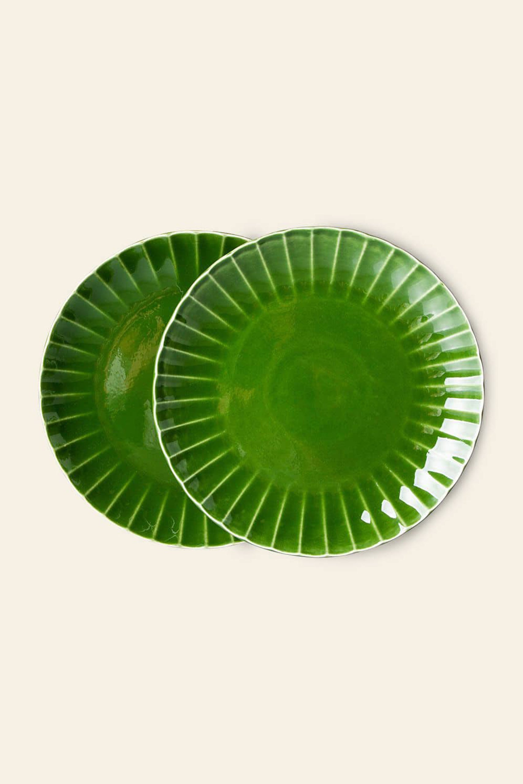 Two HKliving The Emeralds: Ceramic Dinner Plate Ribbed, Set of 2—round, emerald green plates with a glossy ribbed design—overlap slightly on a plain beige background.
