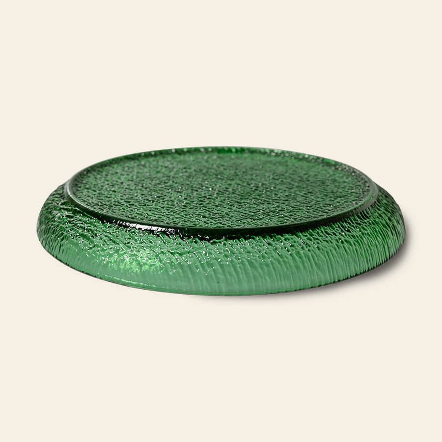 The HKliving The Emeralds: Glass Side Plate features an emerald green, textured design with slightly raised edges—ideal for stylish dinner parties. Shown against a light beige background.
