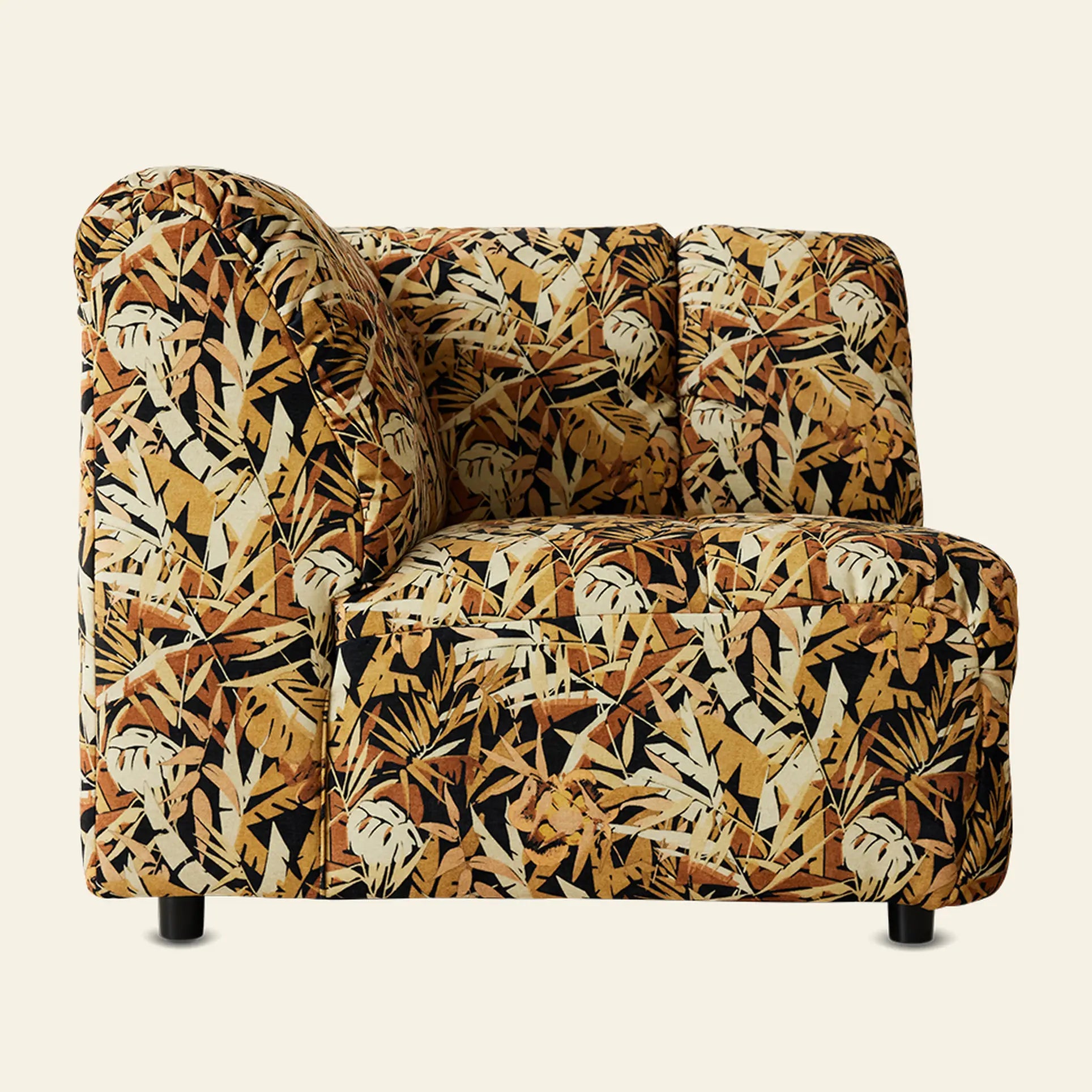 The HKliving Wave Couch, Corner by HKliving is a plush, armless sofa with a high back and seat, upholstered in a bold tropical leaf pattern in yellow, brown, black, and cream, shown against a plain light background.