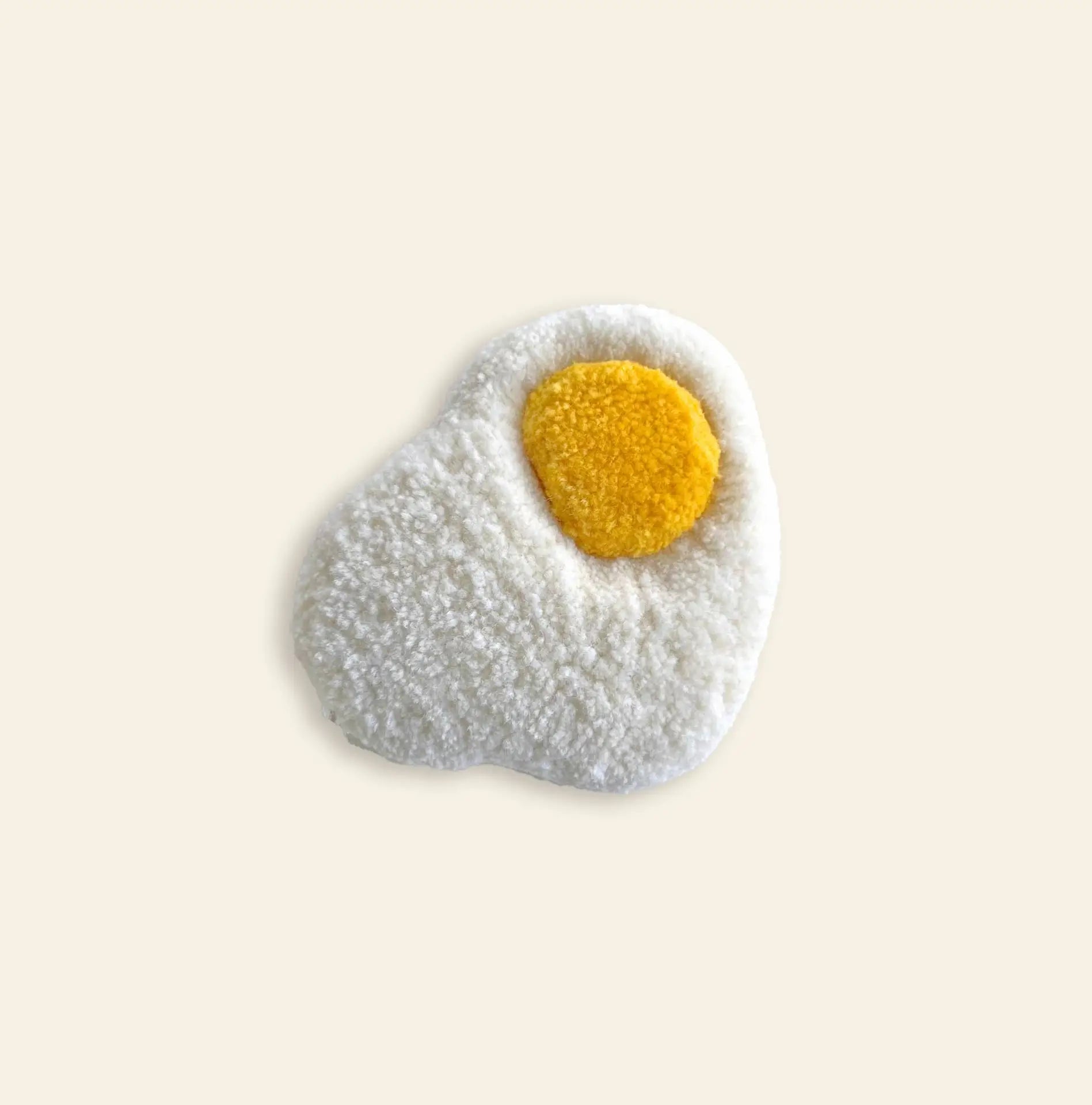 The Habichl Tufted Egg Coaster by Habichl features a handcrafted, textured look with a fluffy white base and round yellow center, designed to resemble a sunny side up egg and shown on a simple light background.