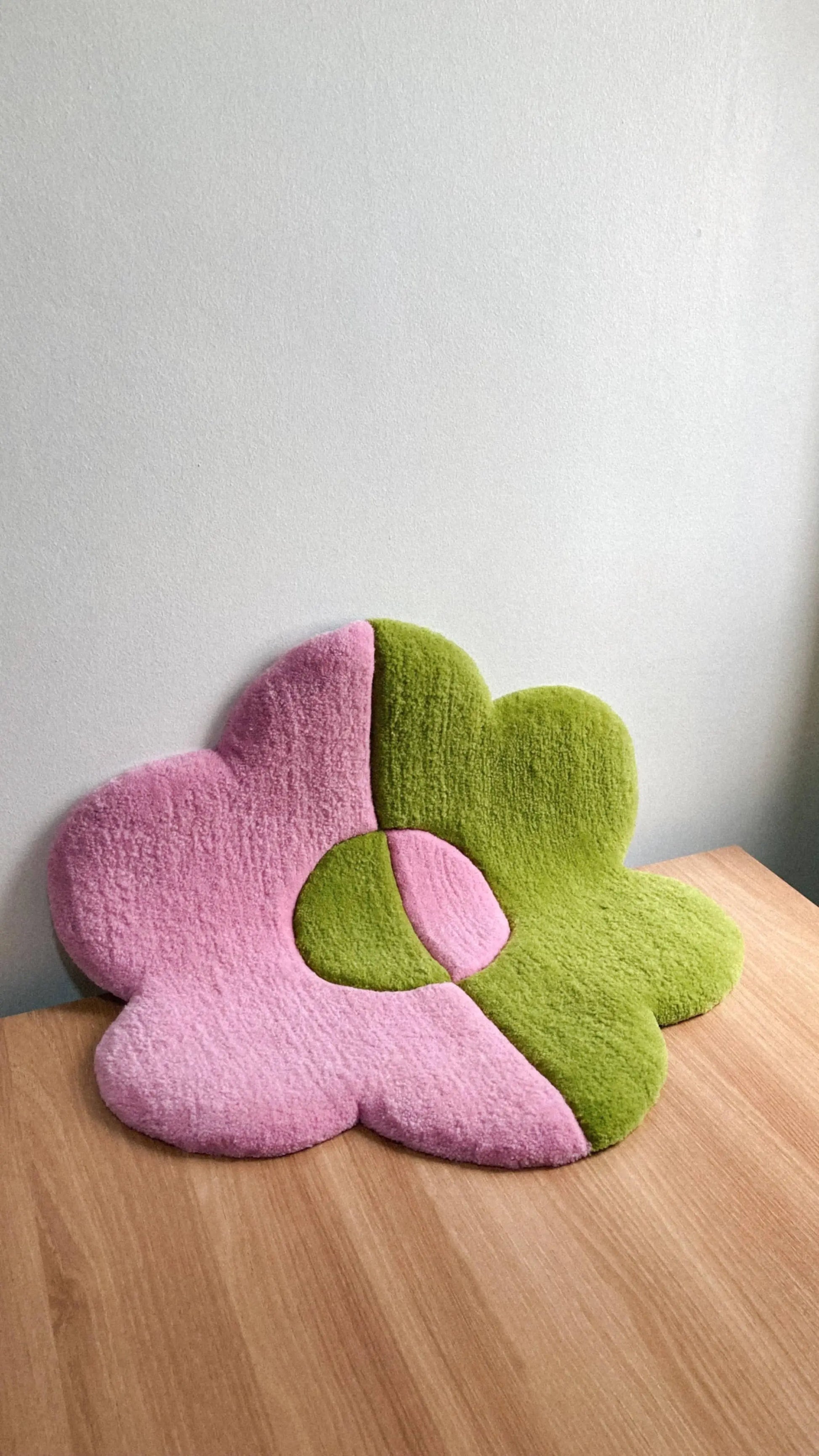 The Habichl Tufted Flower Floor Rug by Habichl features plush pink and green petals with a round center, adding whimsical charm when placed against a light gray wall on any wooden surface.