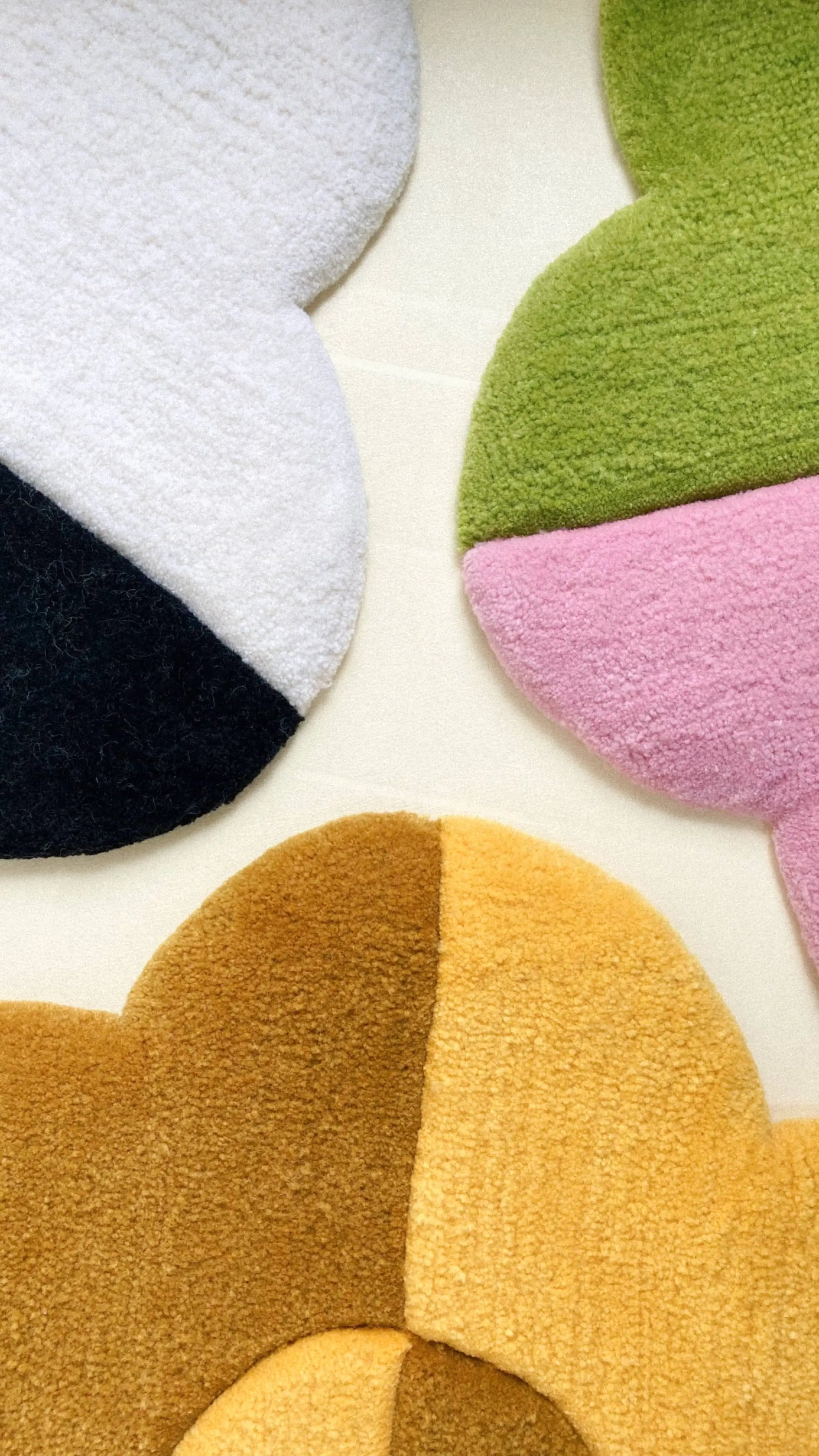 The Habichl Tufted Flower Floor Rugs by Habichl, in white/black, green/pink, and yellow/brown, feature soft textures and abstract floral shapes—bringing a whimsical touch to any space with their light background design.