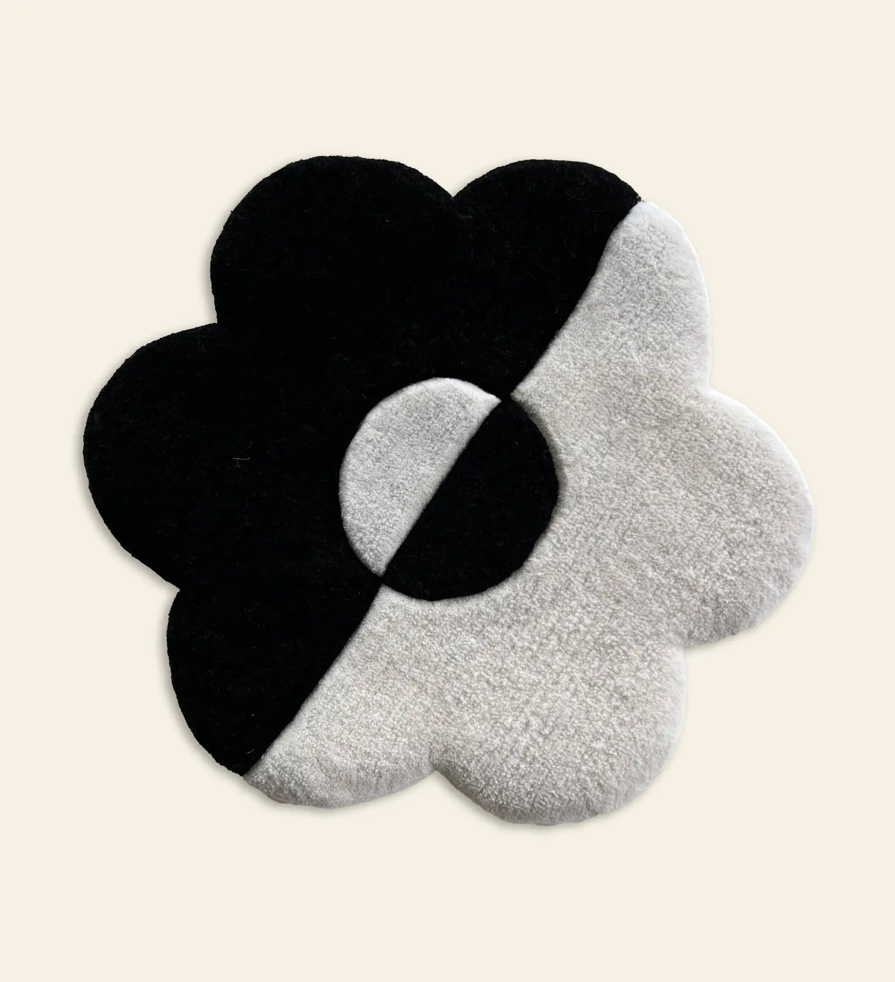 The Habichl Tufted Flower Floor Rug by Habichl features a whimsical flower shape divided diagonally into black and white halves with a matching center, all set on a light beige background.