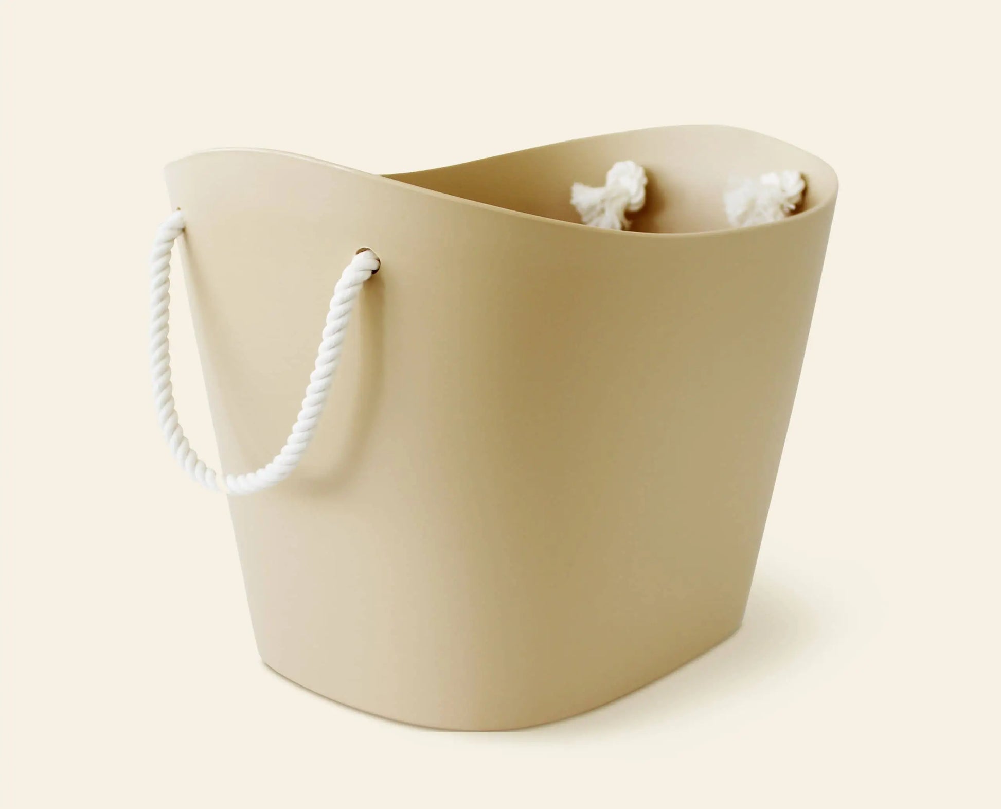 The Hachiman Balcolore Storage Basket M by Hachiman features a beige, curved design with thick white rope handles, blending minimalist Japanese style with versatile storage against a light backdrop.
