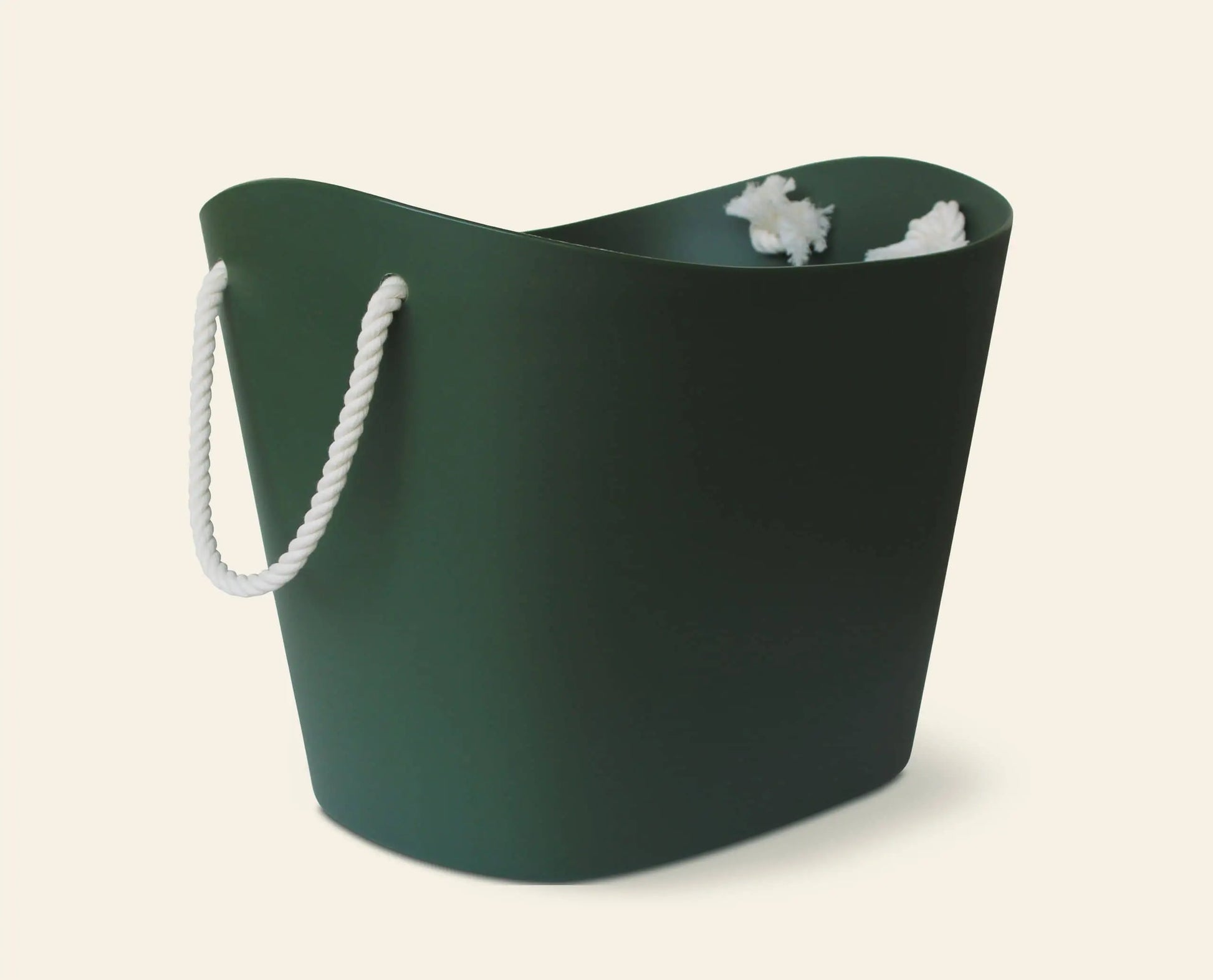 The Hachiman Balcolore Storage Basket M by Hachiman, in dark green with a white rope handle and minimalist Japanese design, holds crumpled white paper. Its modern look fits any space, serving as a versatile storage solution against a light background.
