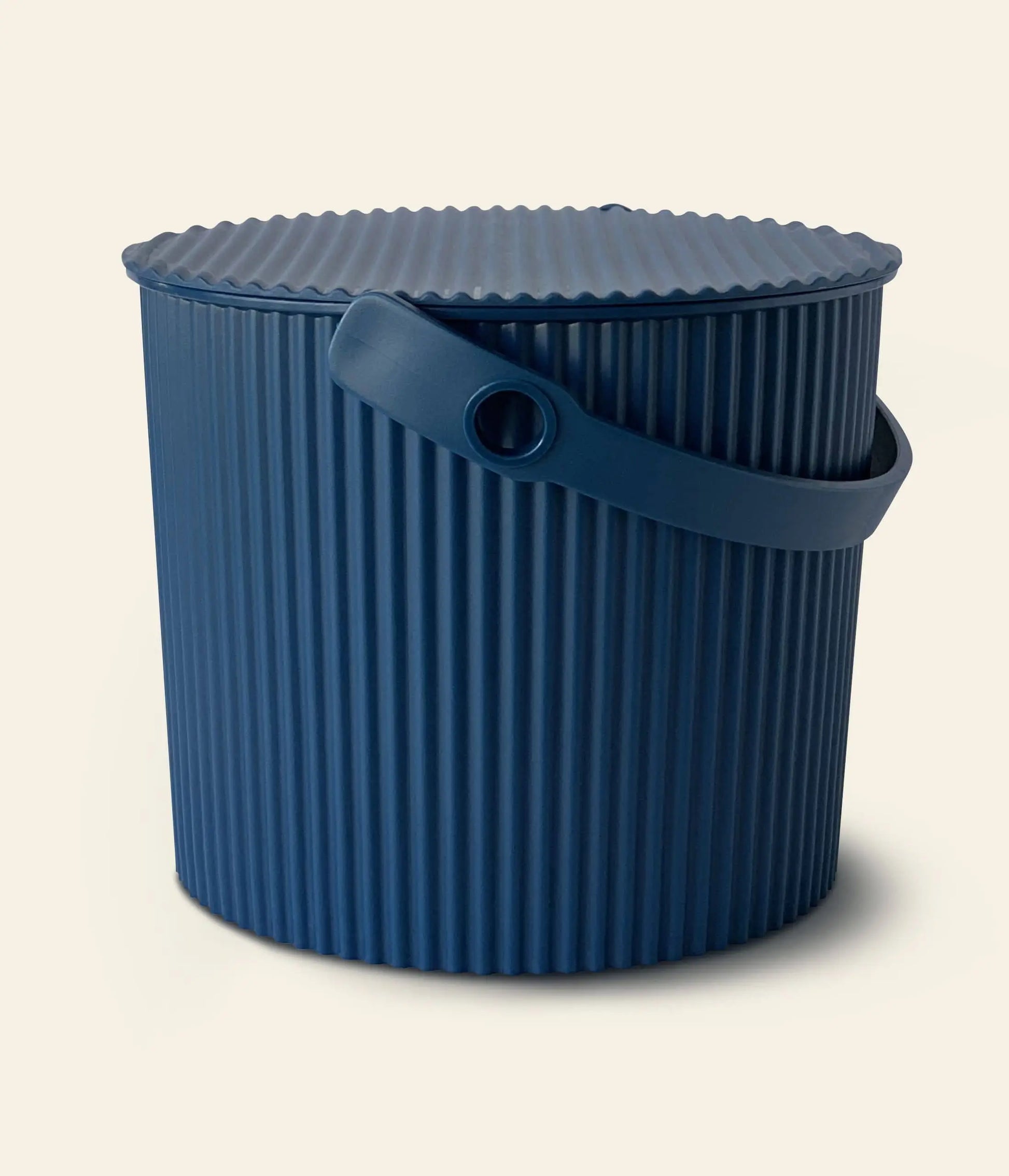 A blue Hachiman Omnioutil Storage Bucket S by Hachiman, featuring vertical ridges, a matching round lid, and curved side handle—perfect for indoor or outdoor use—displayed against an off-white background.