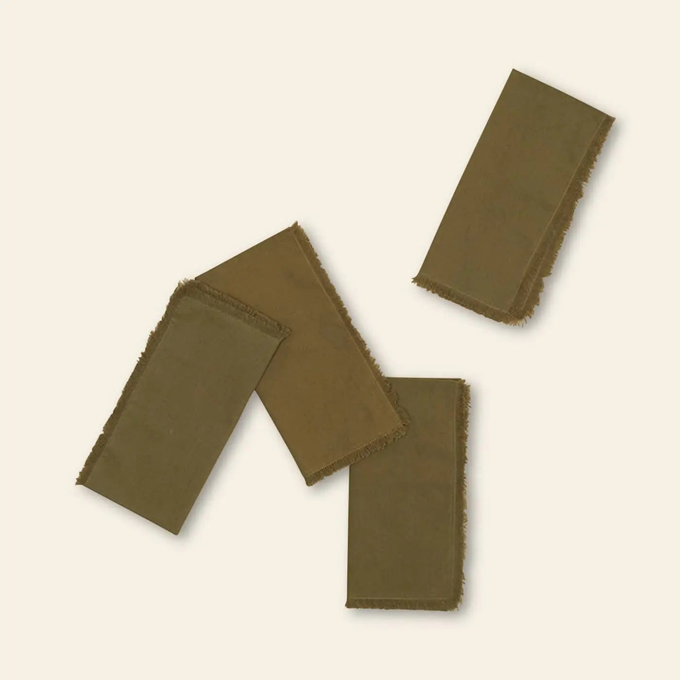 The Hawkins New York Essential Dinner Napkins, Set of 4, feature olive-green cloth with frayed edges. Scattered on a light beige background, they add charm and elegance to any table setting.