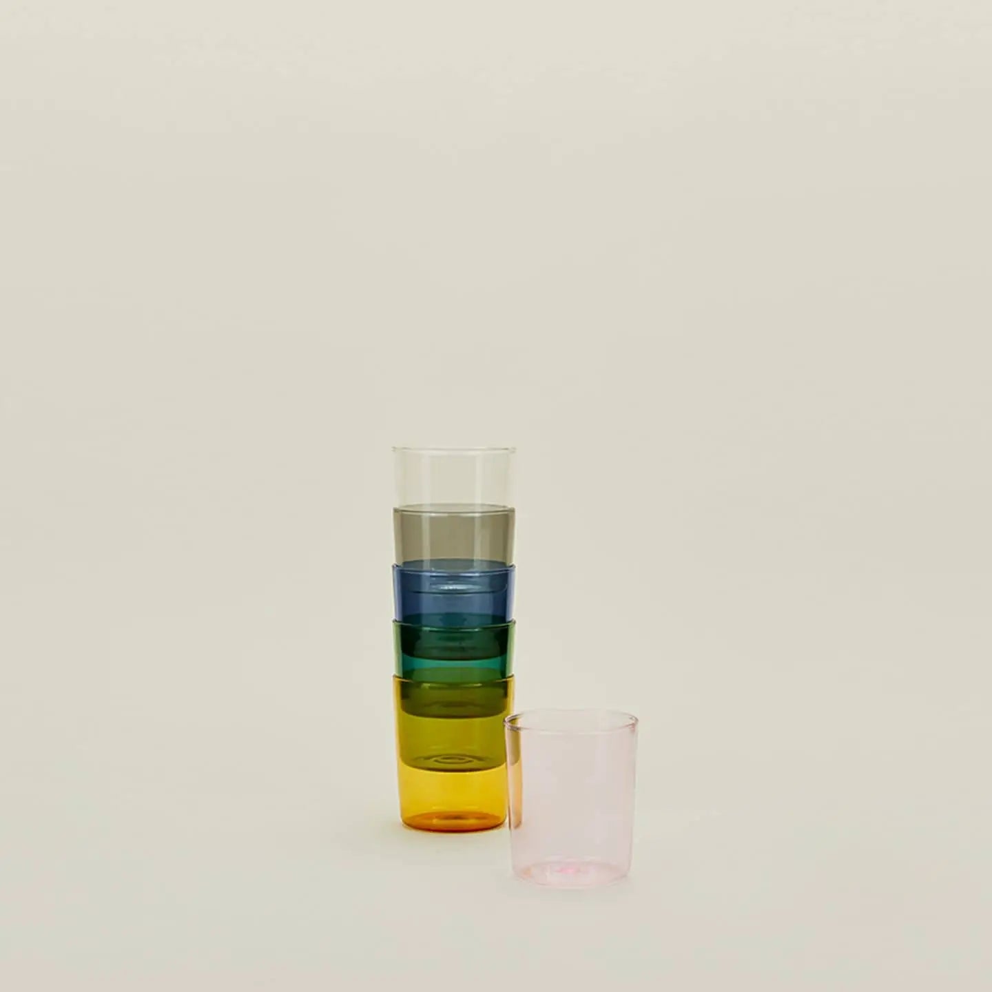 The Hawkins New York Essential Glassware, Set of 4, Medium features colorful cups stacked together, with a separate pink cup adding style and versatility to any setting.