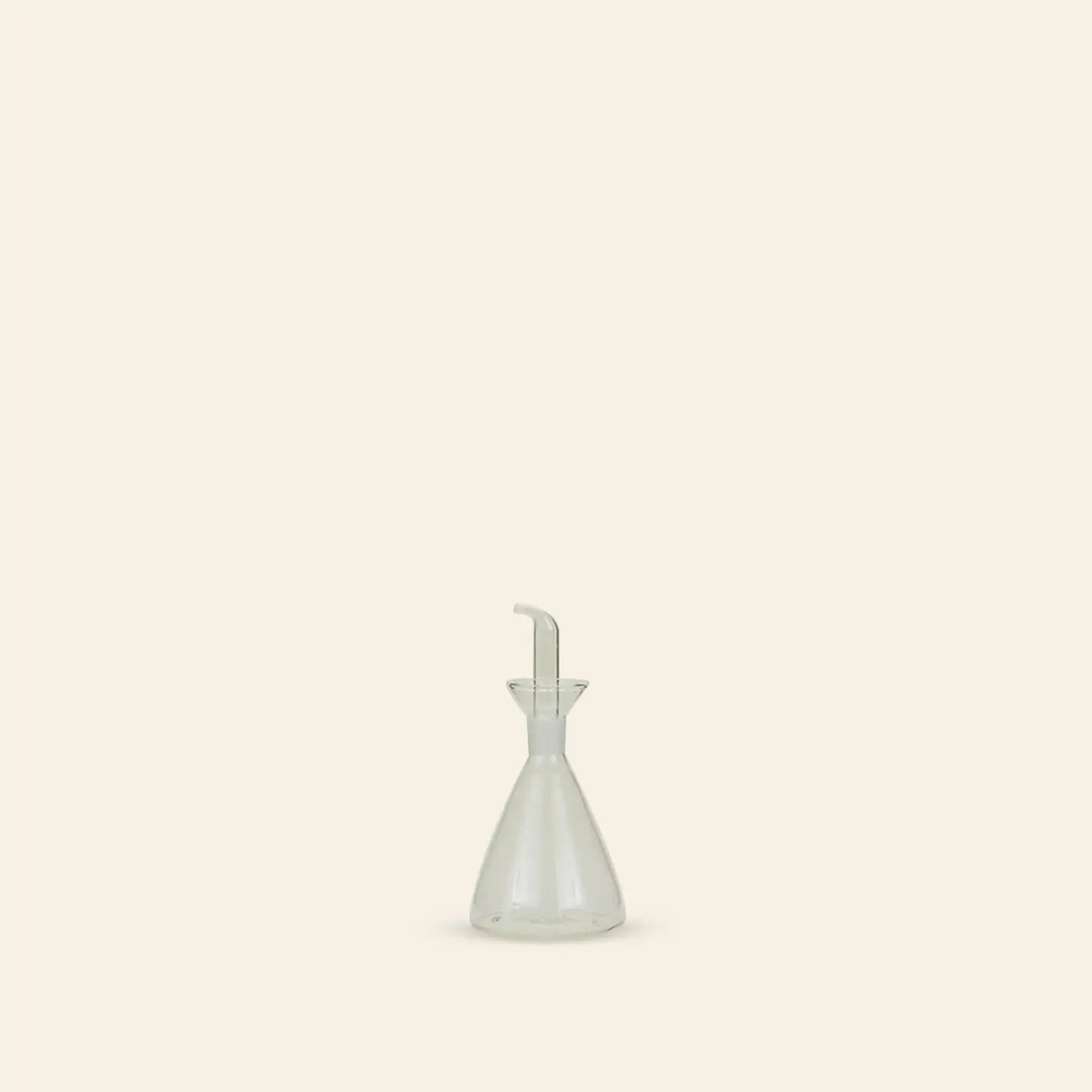 The Hawkins New York Essential Kitchen Bottle, Medium, with modern styling and a precision drizzle spout, sits centered on a light beige background—minimalistic and refined for controlled pouring in any contemporary kitchen.